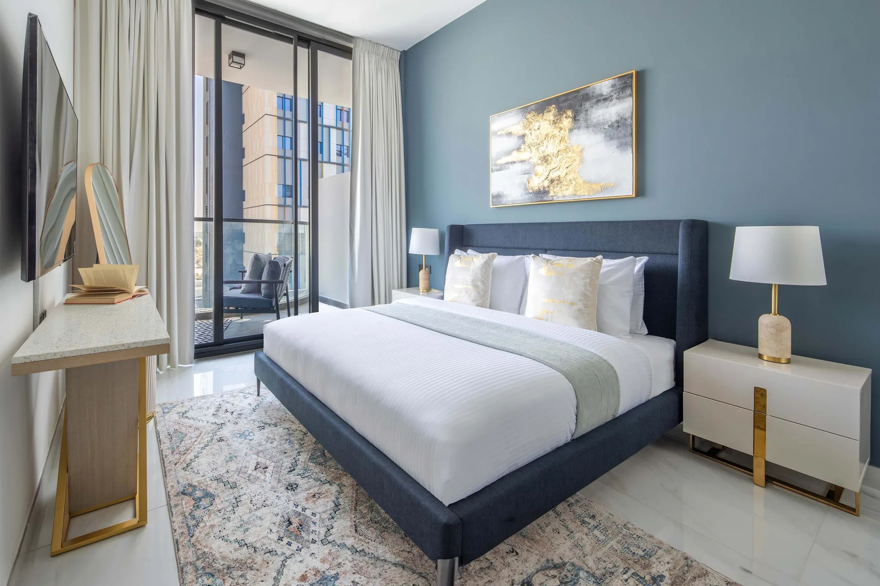 A bedroom with a neatly made bed, bedside tables, and a large window.
