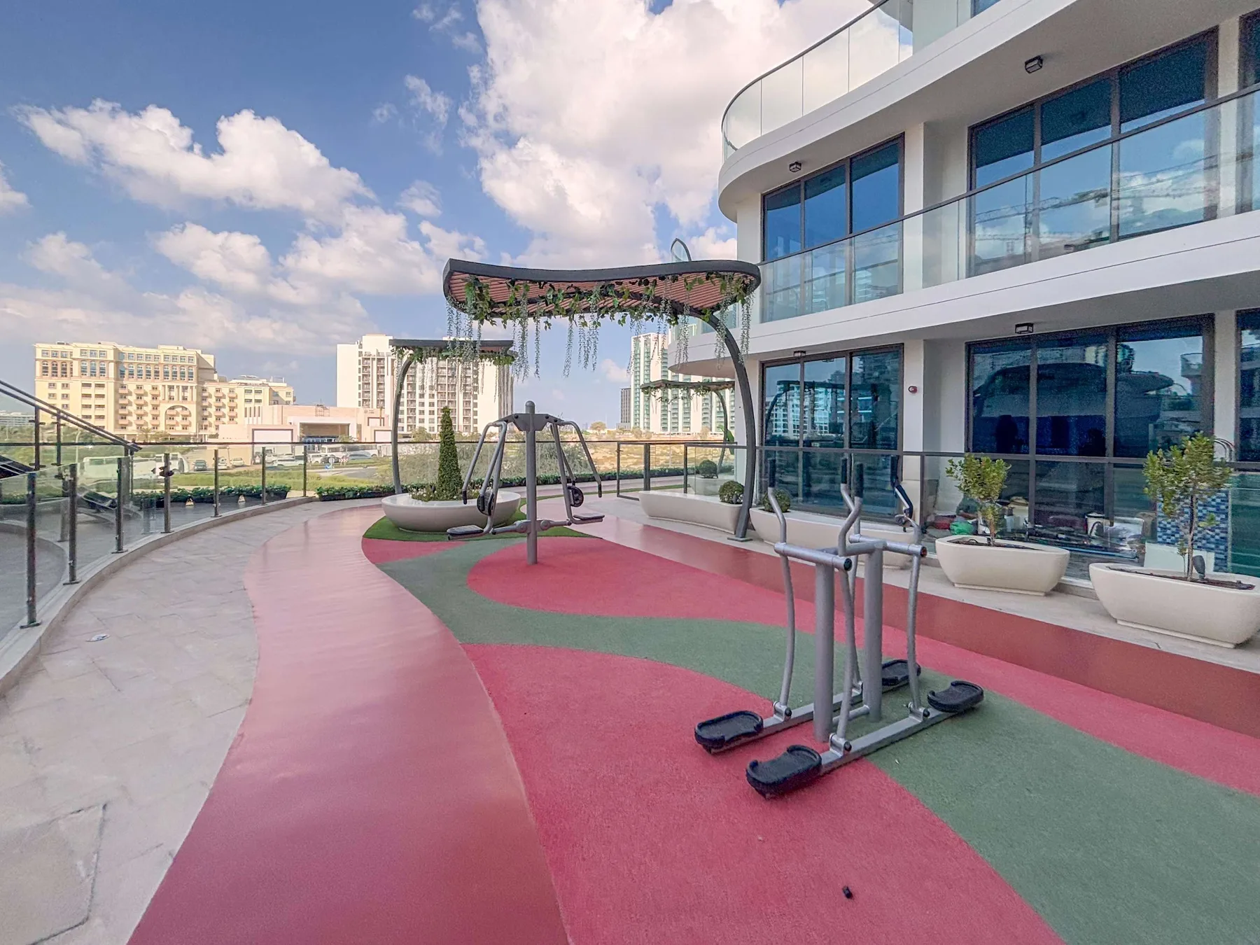 An outdoor rooftop fitness area with exercise equipment beside a modern building.