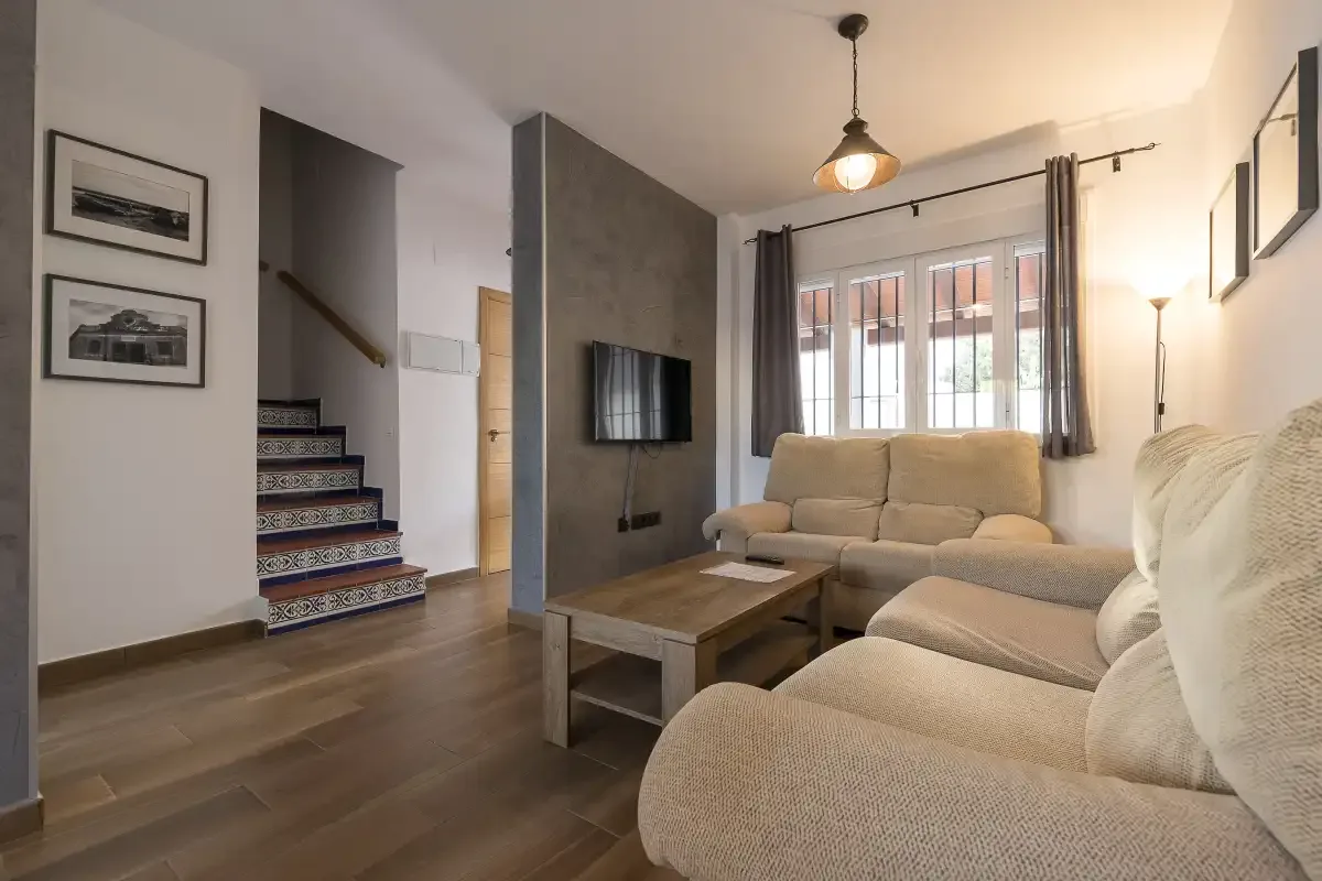 A living room with light-colored seating, a coffee table, and a television.