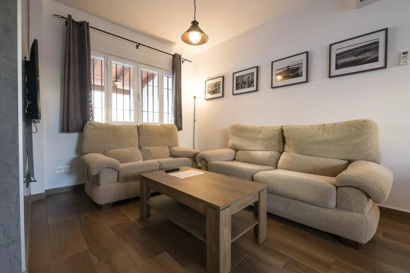 A living room with beige seating, a coffee table, and framed pictures on the wall.