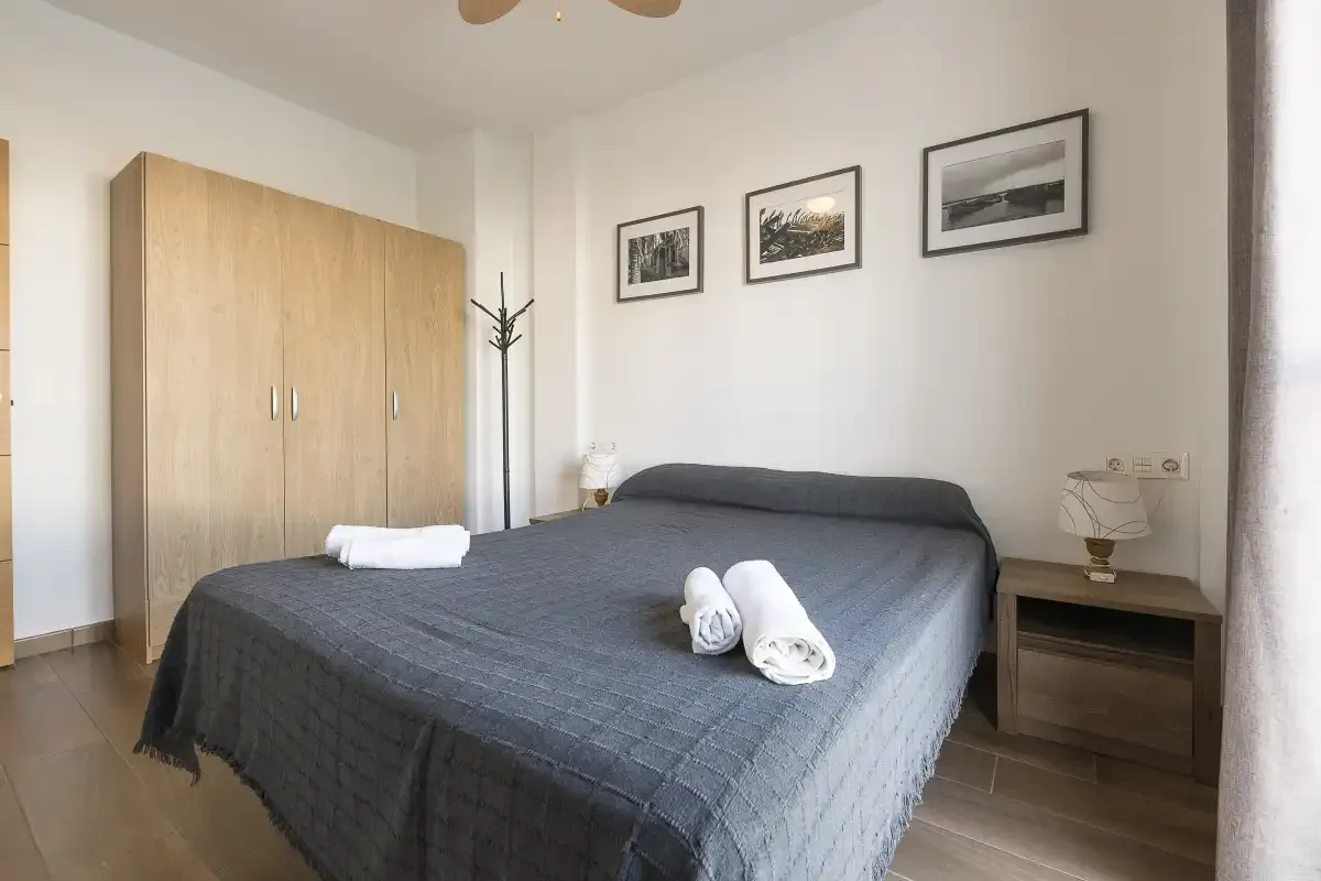 A bedroom with a double bed, wardrobe, and framed pictures on the wall.