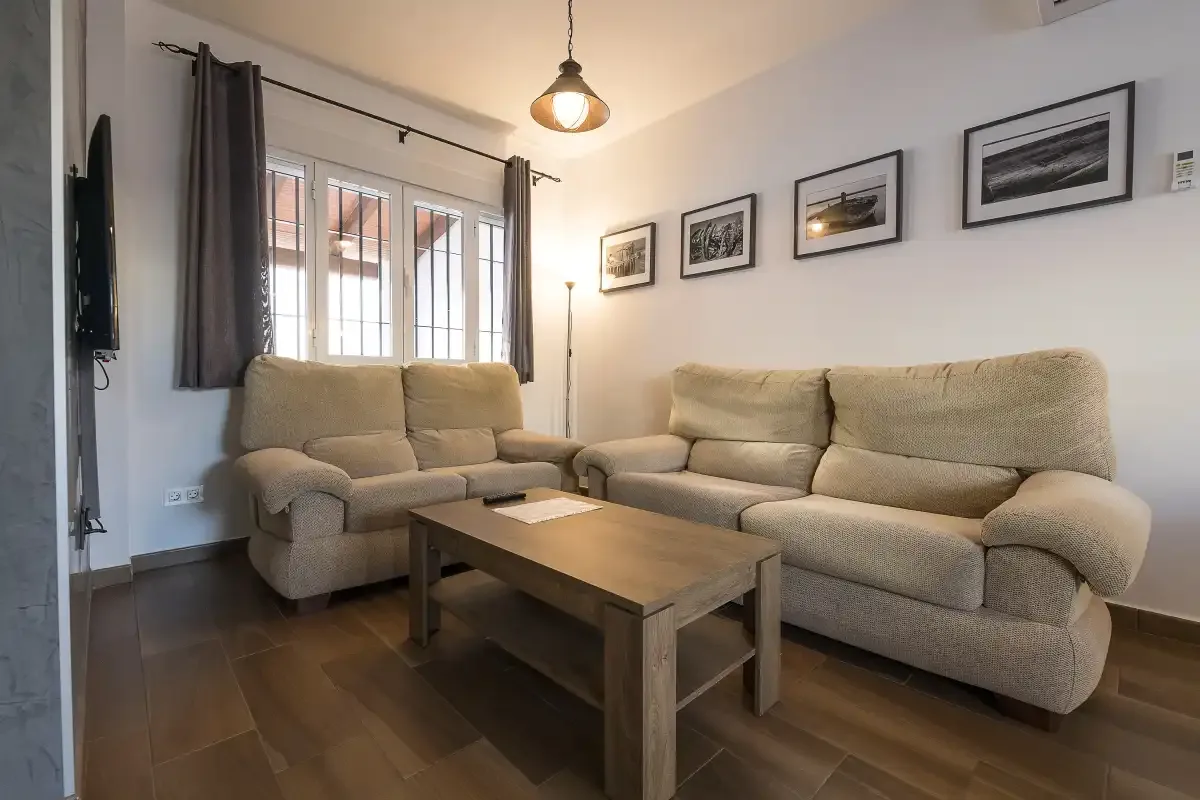 A living room with beige seating, a wooden coffee table, and framed pictures.