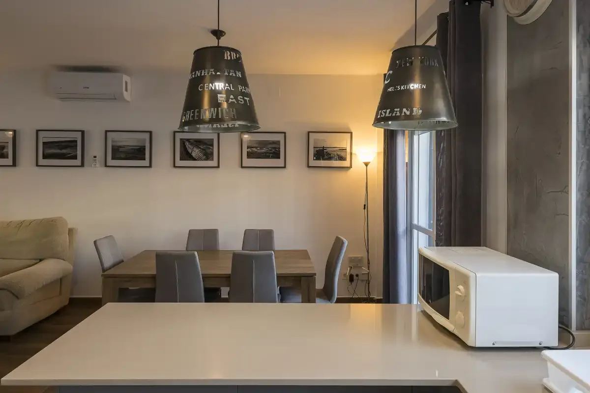 A dining area with a table, seating, and a microwave on the counter.