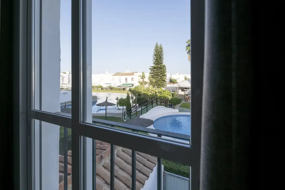 A window overlooks an outdoor pool and landscaped courtyard.