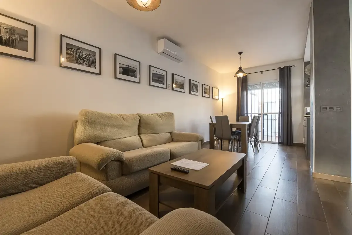 A living and dining area with sofas, a coffee table, and a dining table by the windows.