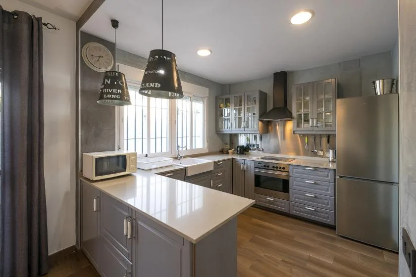 A modern kitchen with gray cabinets, a central island, and stainless steel appliances.
