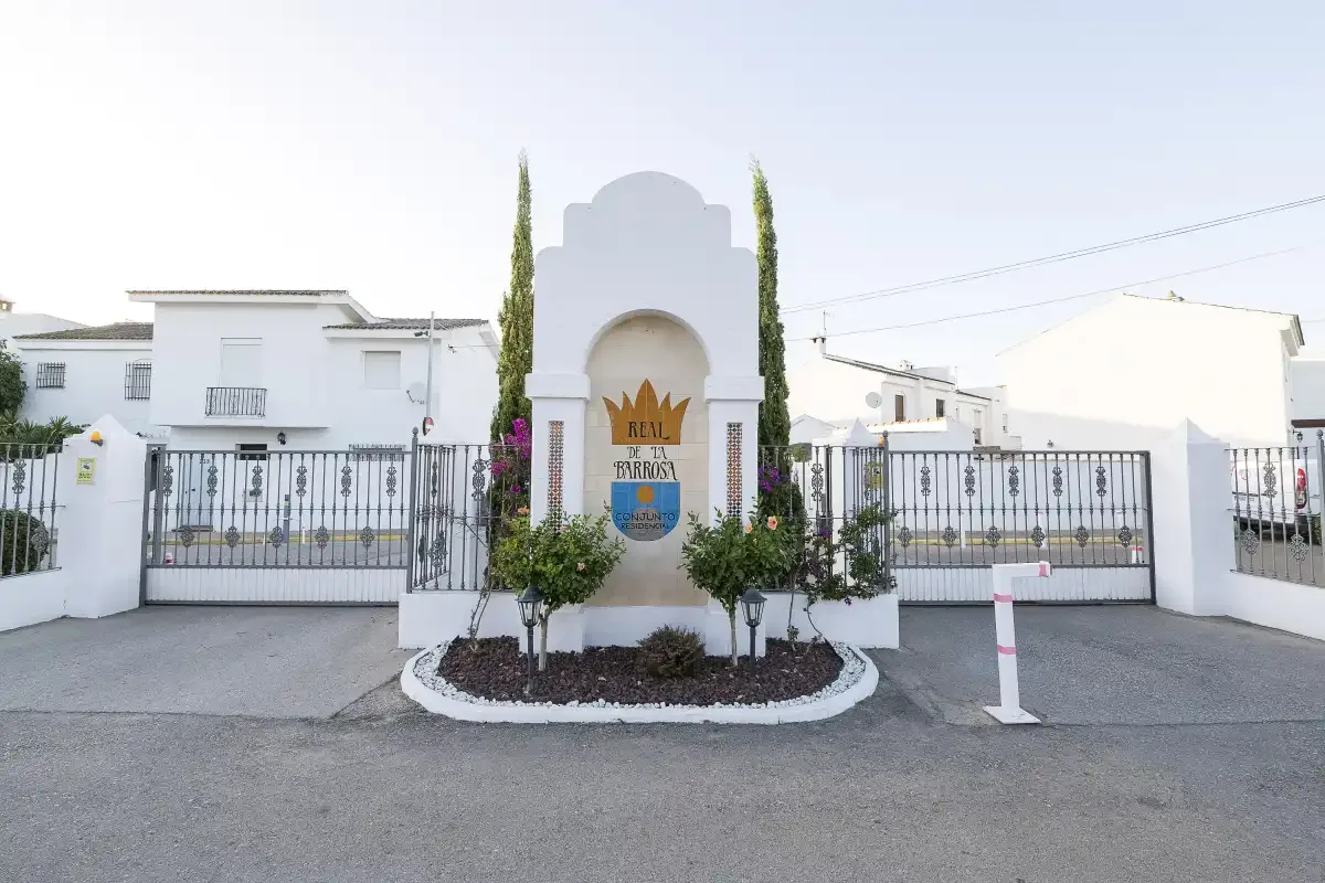 A white entrance monument stands between gated residential buildings.