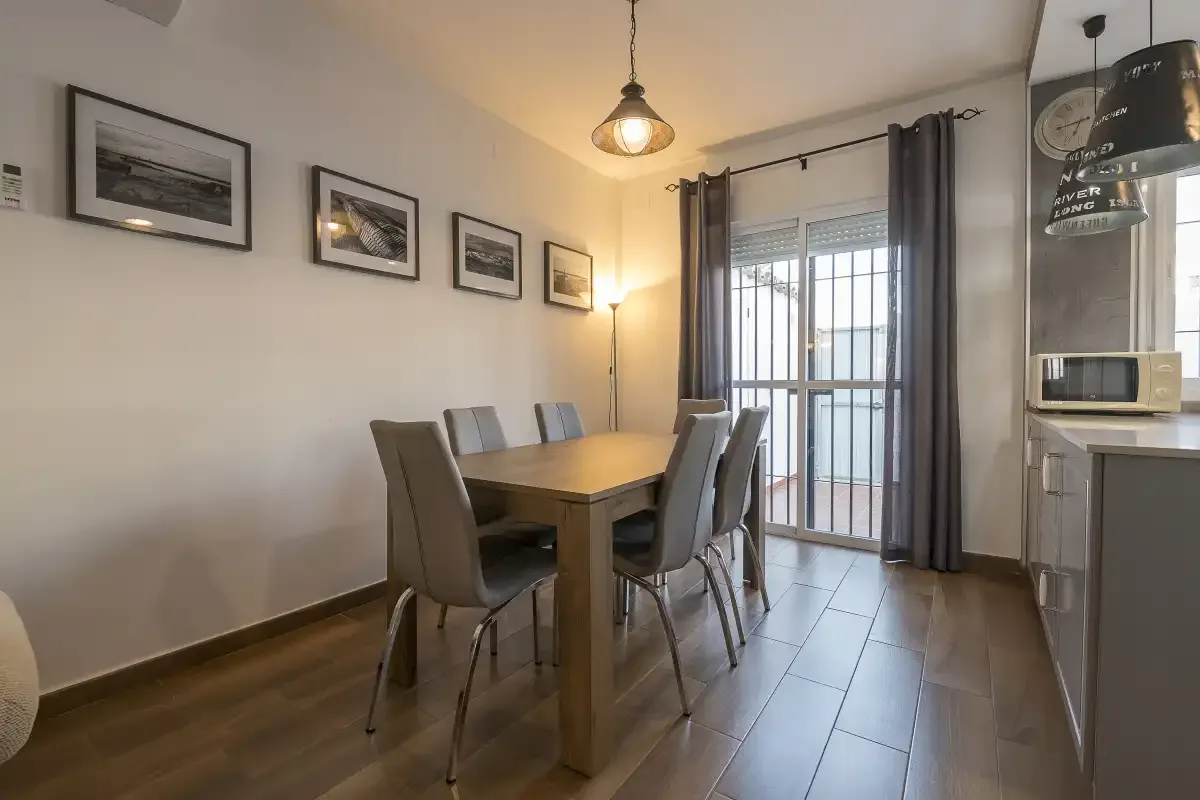 A dining area with a table and seating beside a glass balcony door.