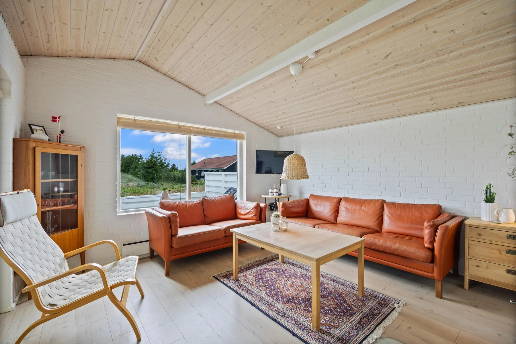 A living room with orange seating, a coffee table, and a large window.