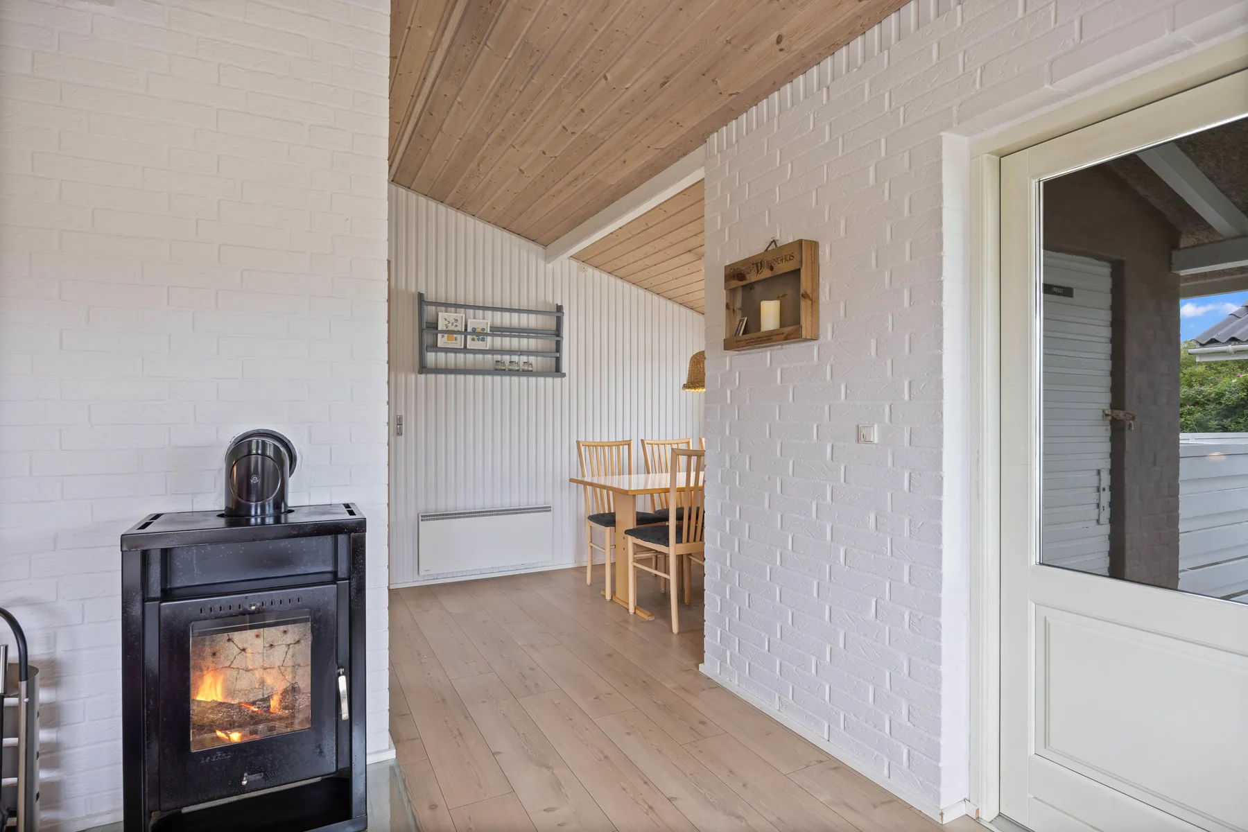 A bright dining area with a wooden table beside a black stove.