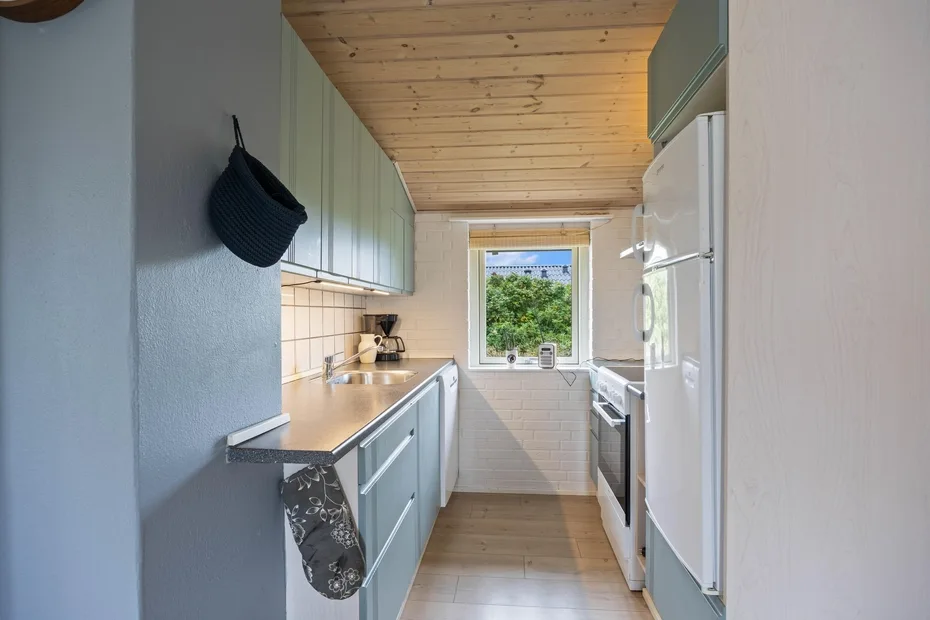 A narrow kitchen with counters and cabinets along both sides.