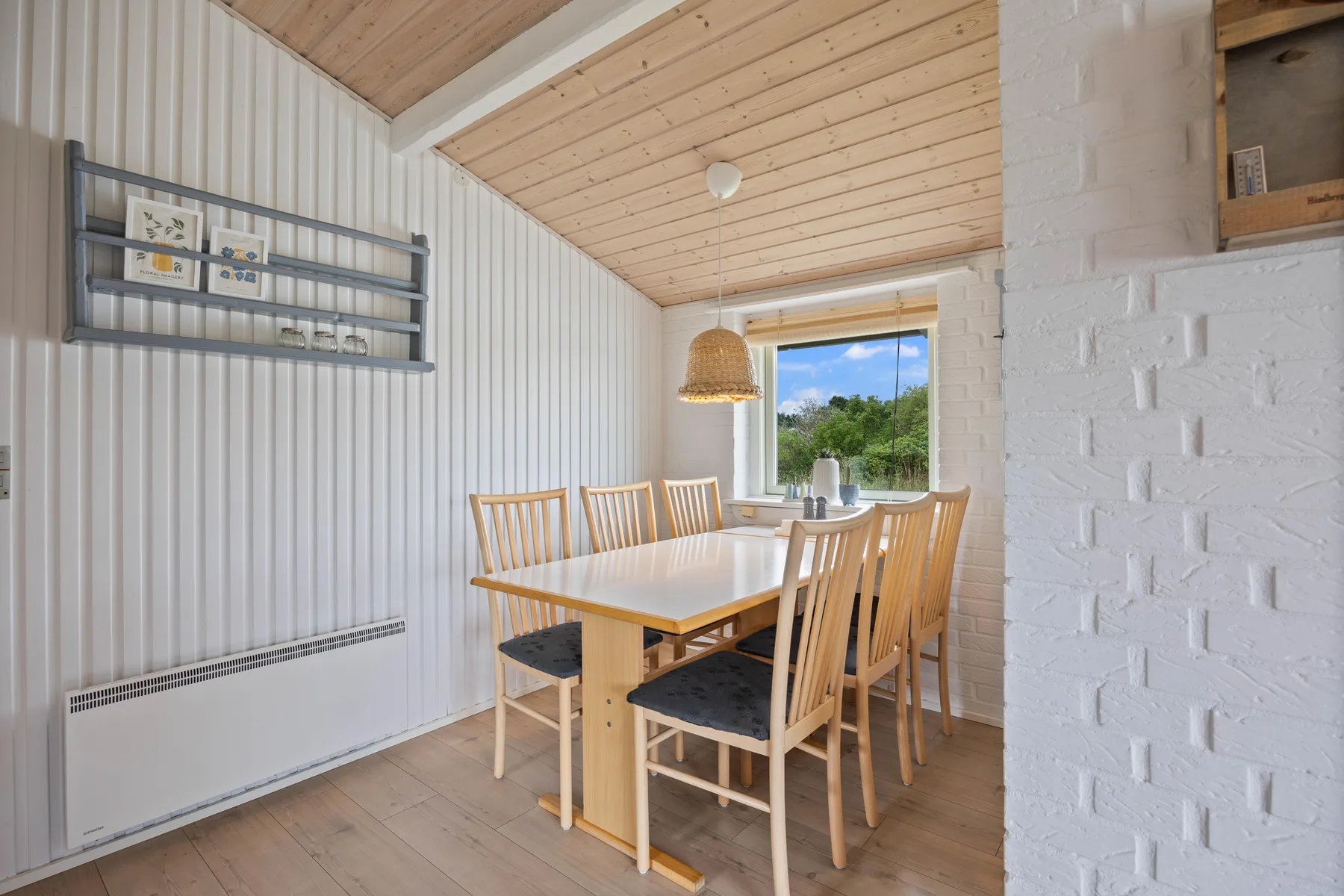 Dining area with a wooden table and chairs beside a large window.