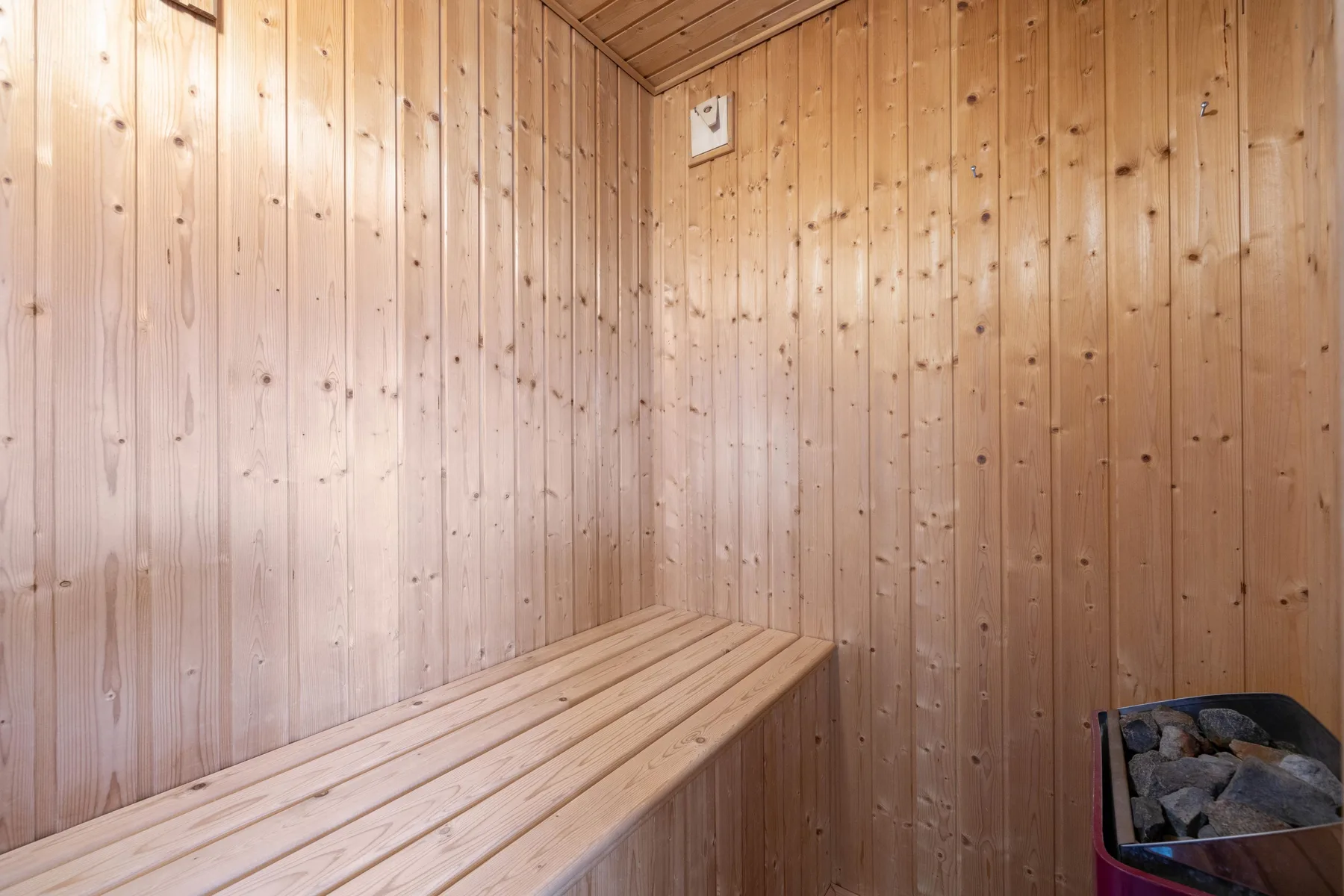 A wood-paneled sauna with a wooden bench and stone heater.