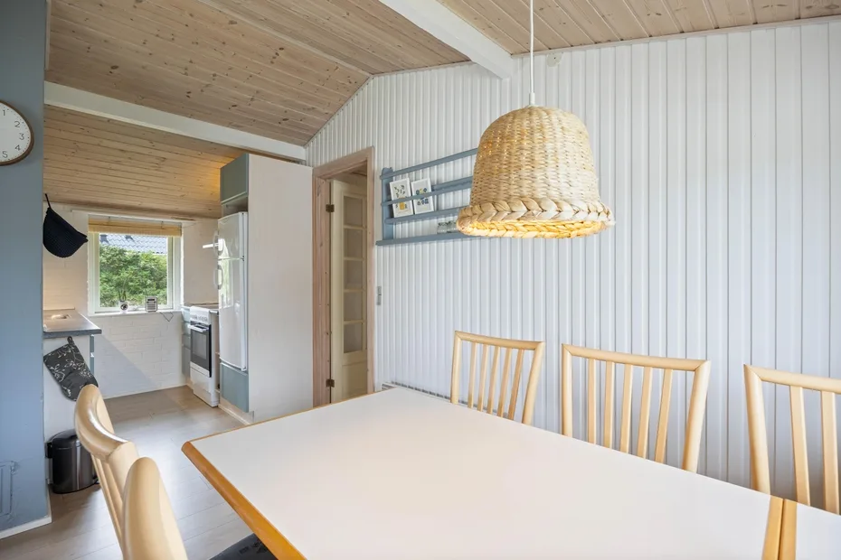 A dining area with a long table and a woven pendant light.
