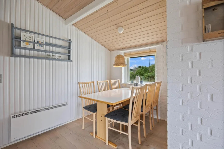 A bright dining area with a wooden table and chairs beside a large window.