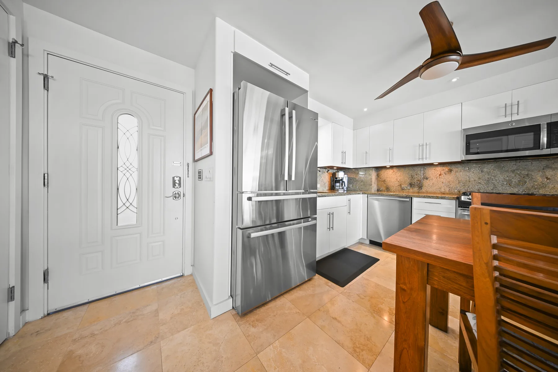Una cocina luminosa con electrodomésticos de acero inoxidable y una mesa de madera.