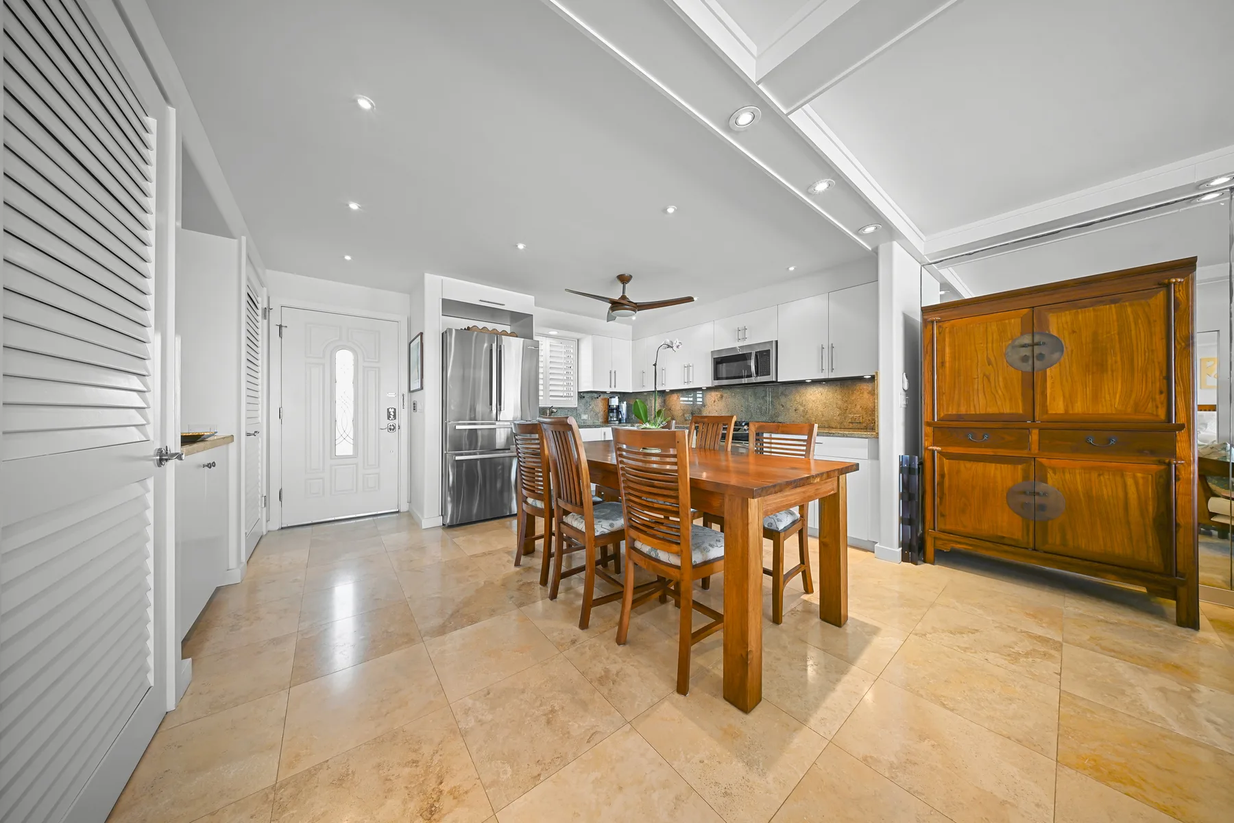 Una cocina luminosa con zona de comedor, mesa de madera y gabinetes blancos.