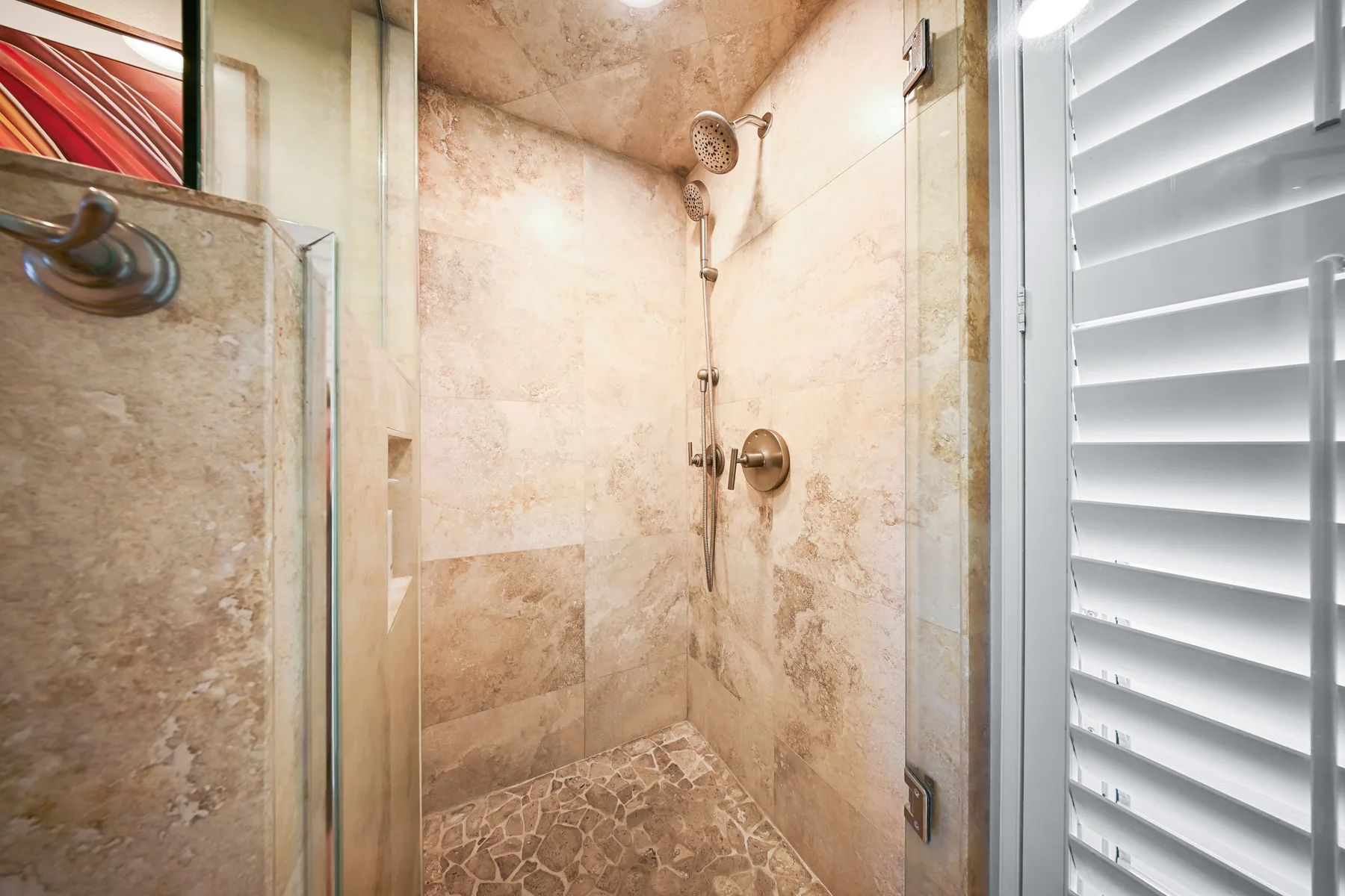 Una ducha revestida de azulejos con ducha de mano y panel de vidrio.