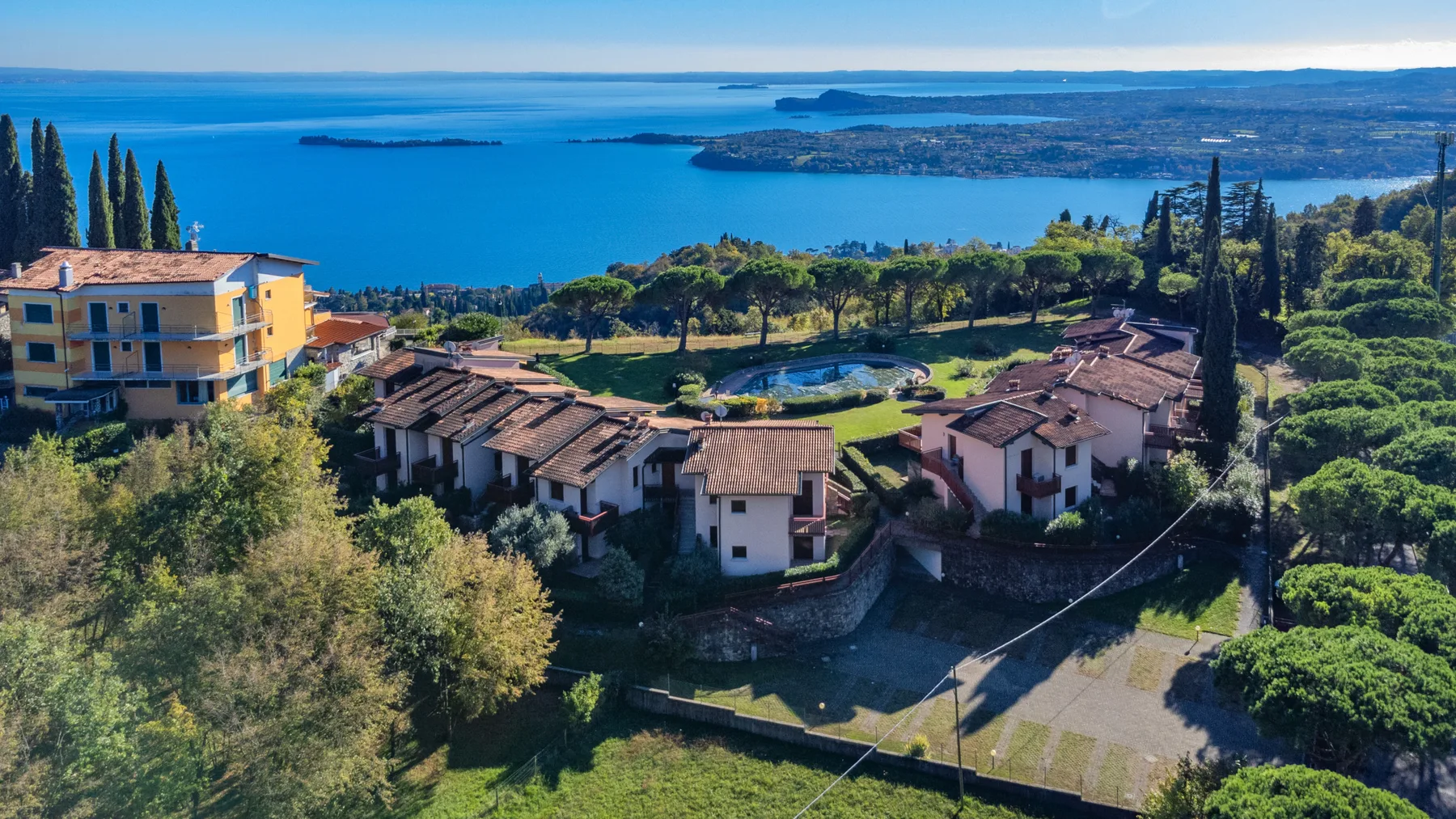 Aerial view of homes among trees overlooking a blue lake.