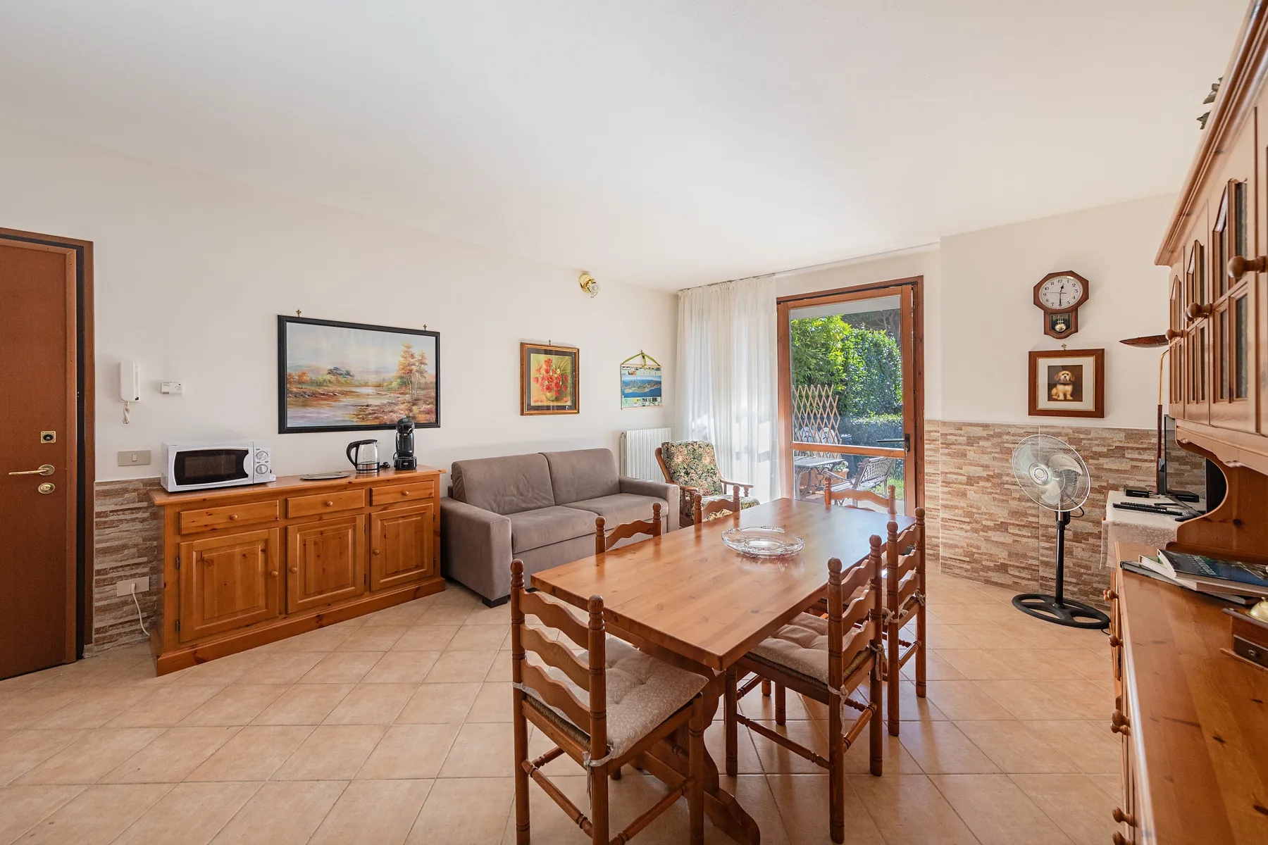 A living and dining room with a wooden table and seating beside a glass door.