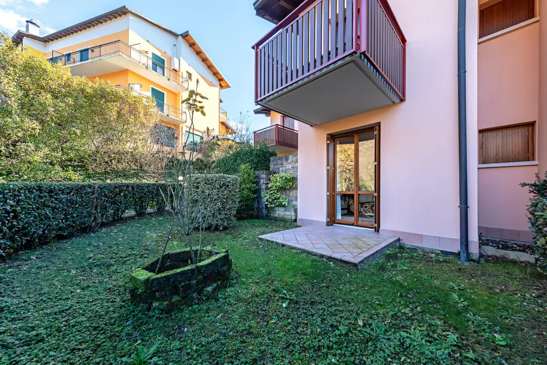 A small garden beside an apartment building, with a patio door and balcony.
