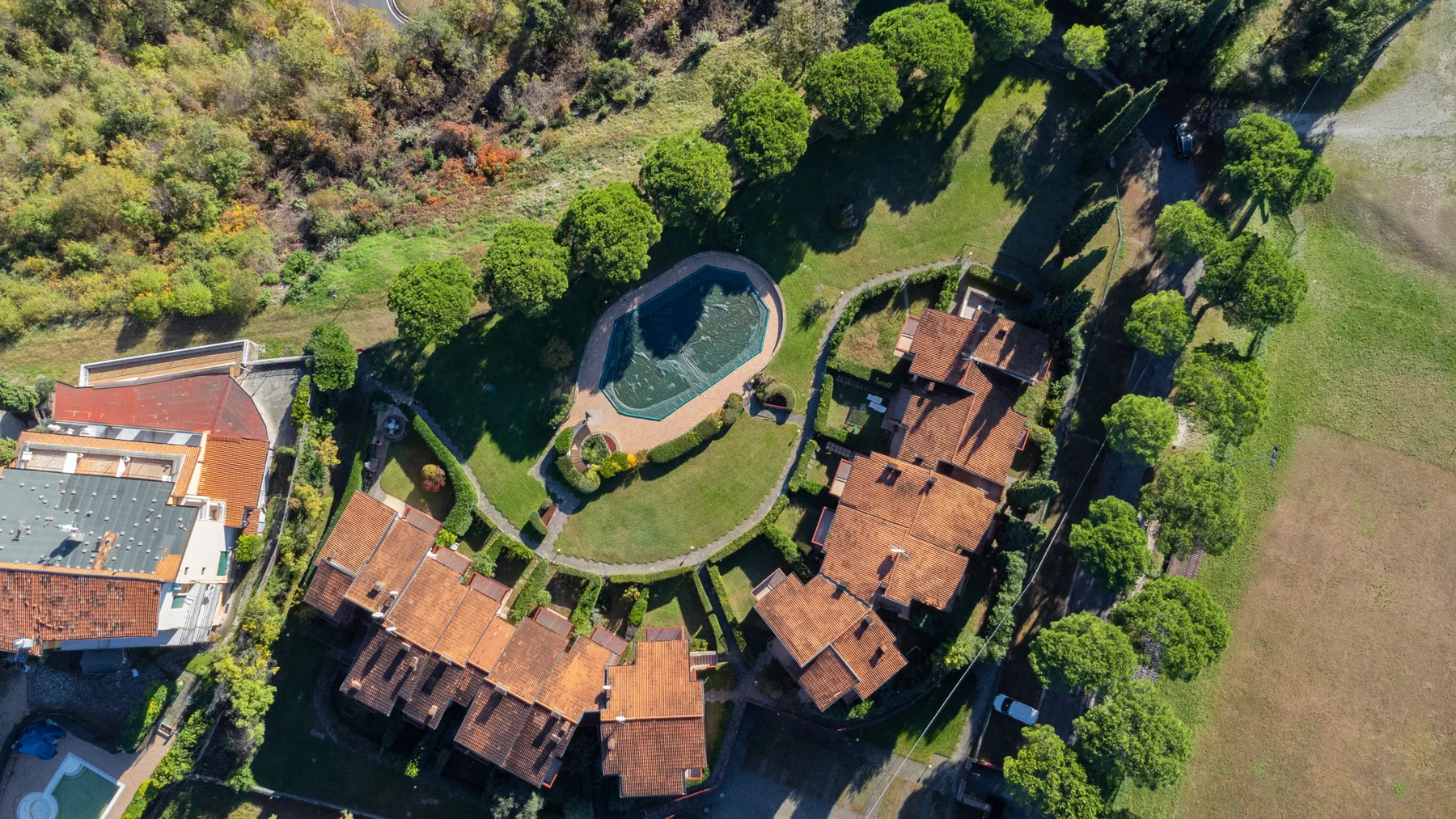 An aerial view of a landscaped property with buildings and a swimming pool.