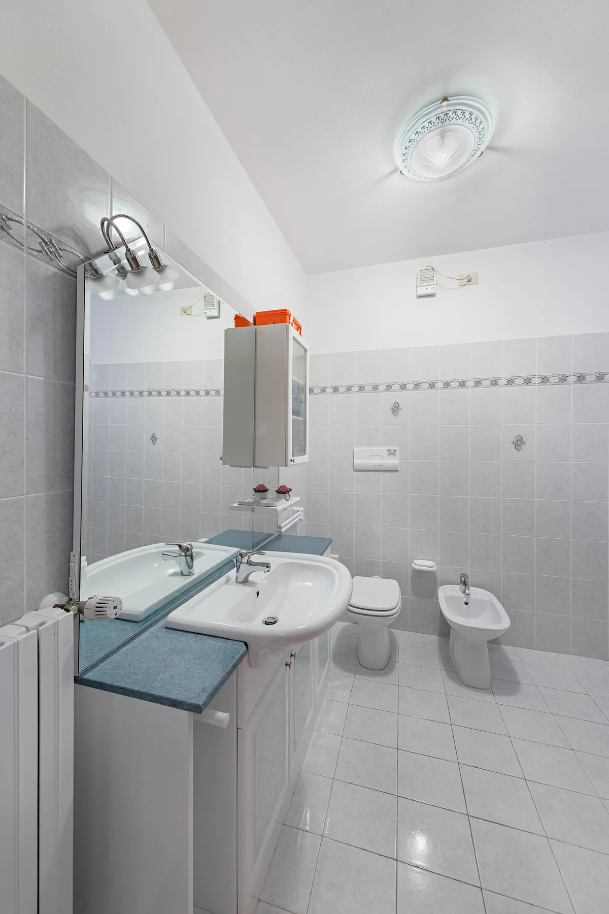 A tiled bathroom with a sink, toilet, bidet, and shower area.