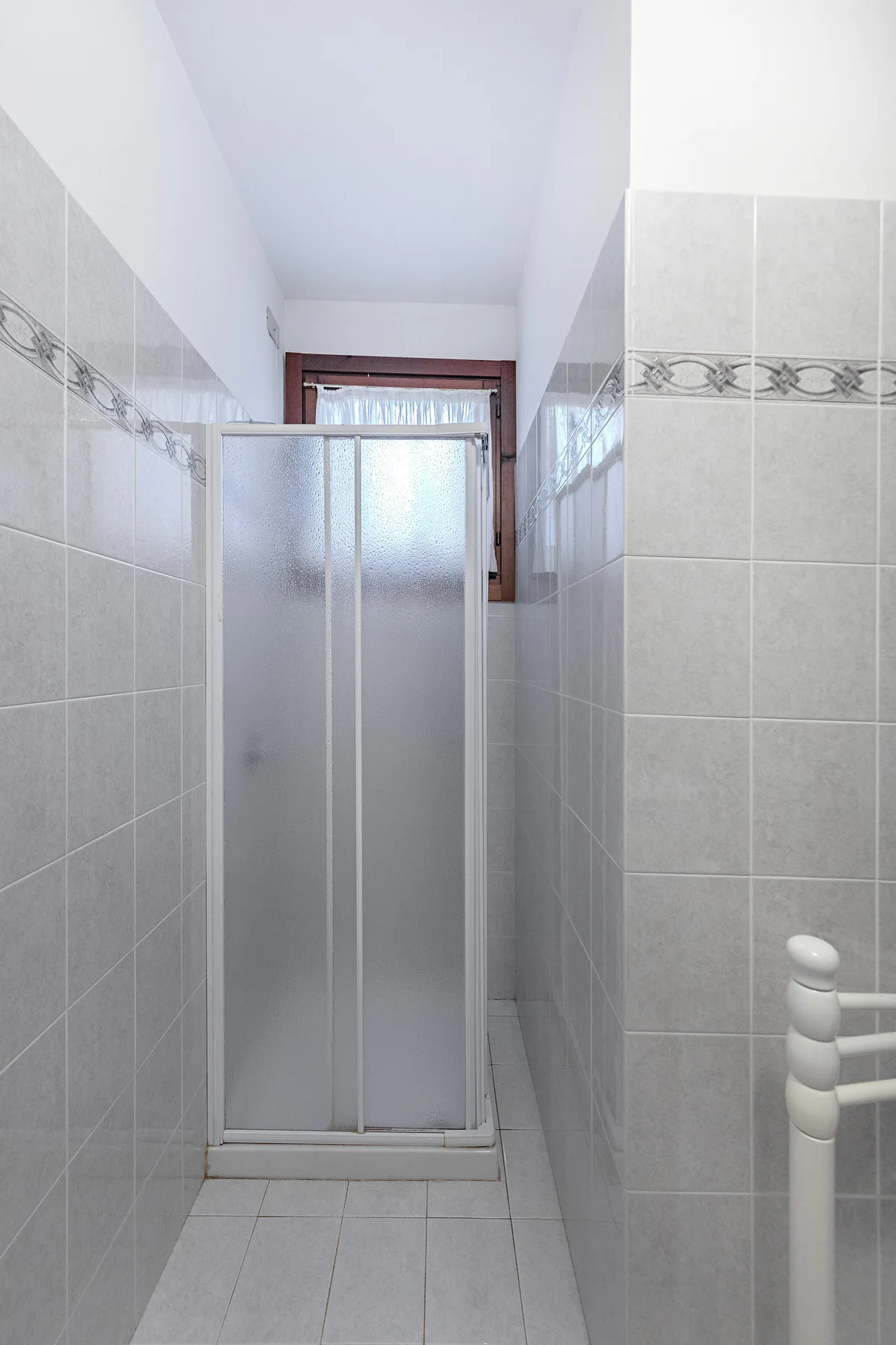 A tiled bathroom with a frosted-glass shower.