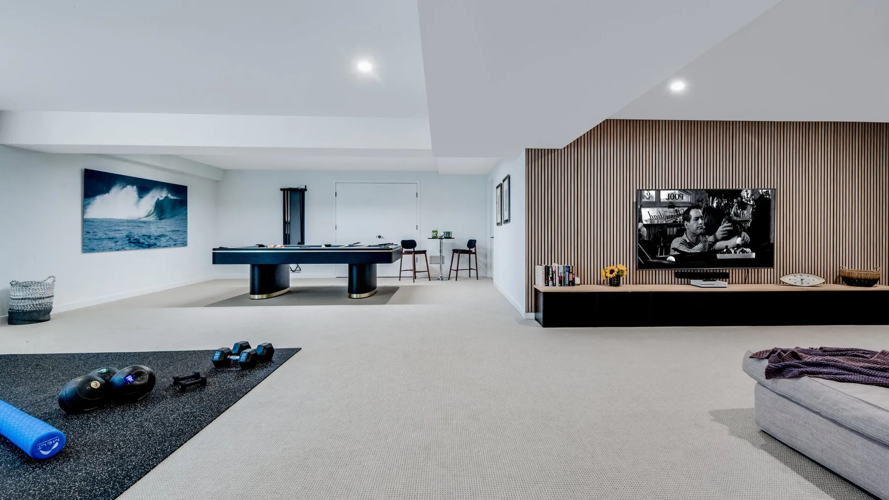 A spacious living room with a pool table, television, and seating area.
