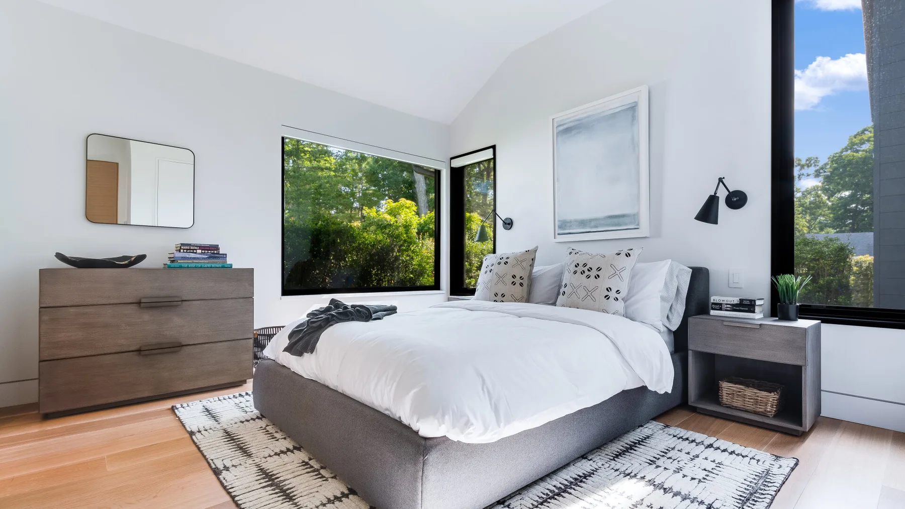 A bright bedroom with a large bed and windows overlooking greenery.