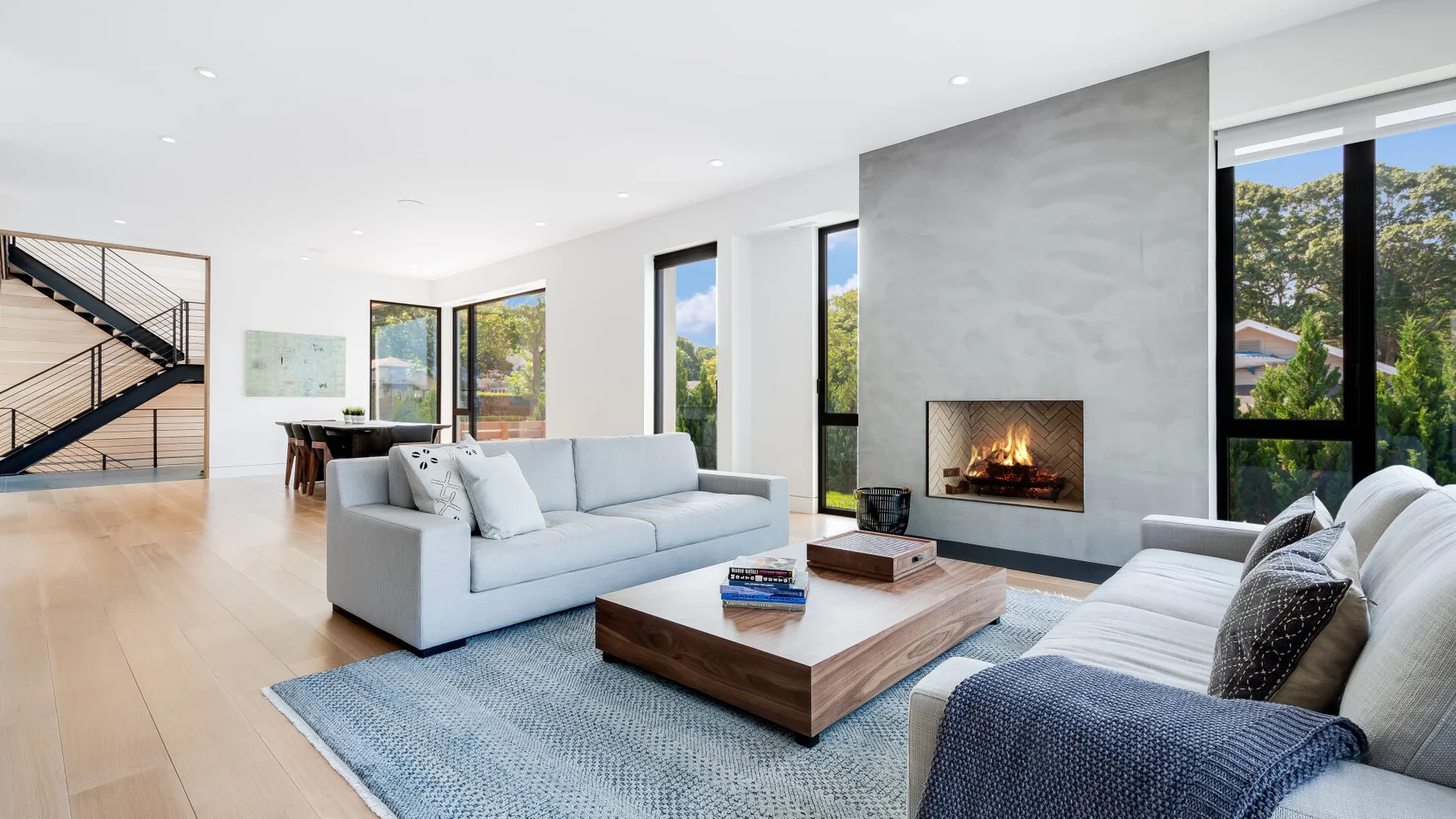 A bright living room with seating arranged around a fireplace and coffee table.