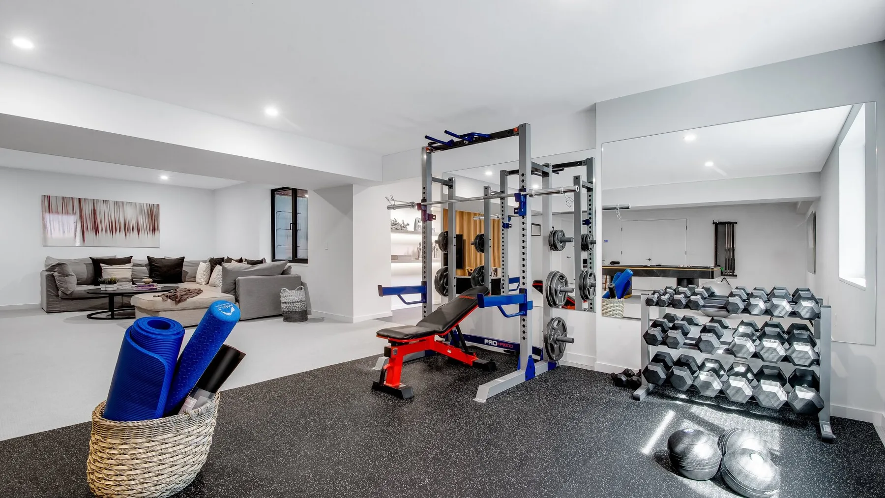 A home gym with weight equipment, dumbbells, and blue exercise mats.