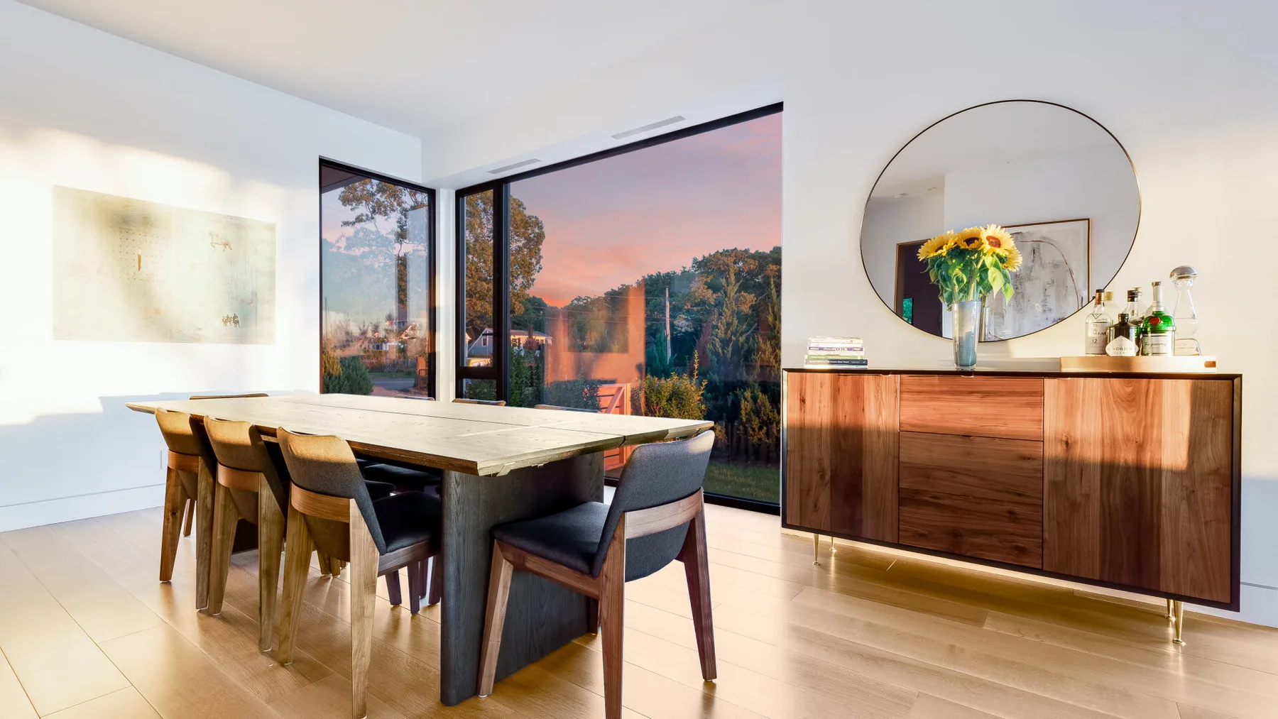 A bright dining area with a long table beside large windows.