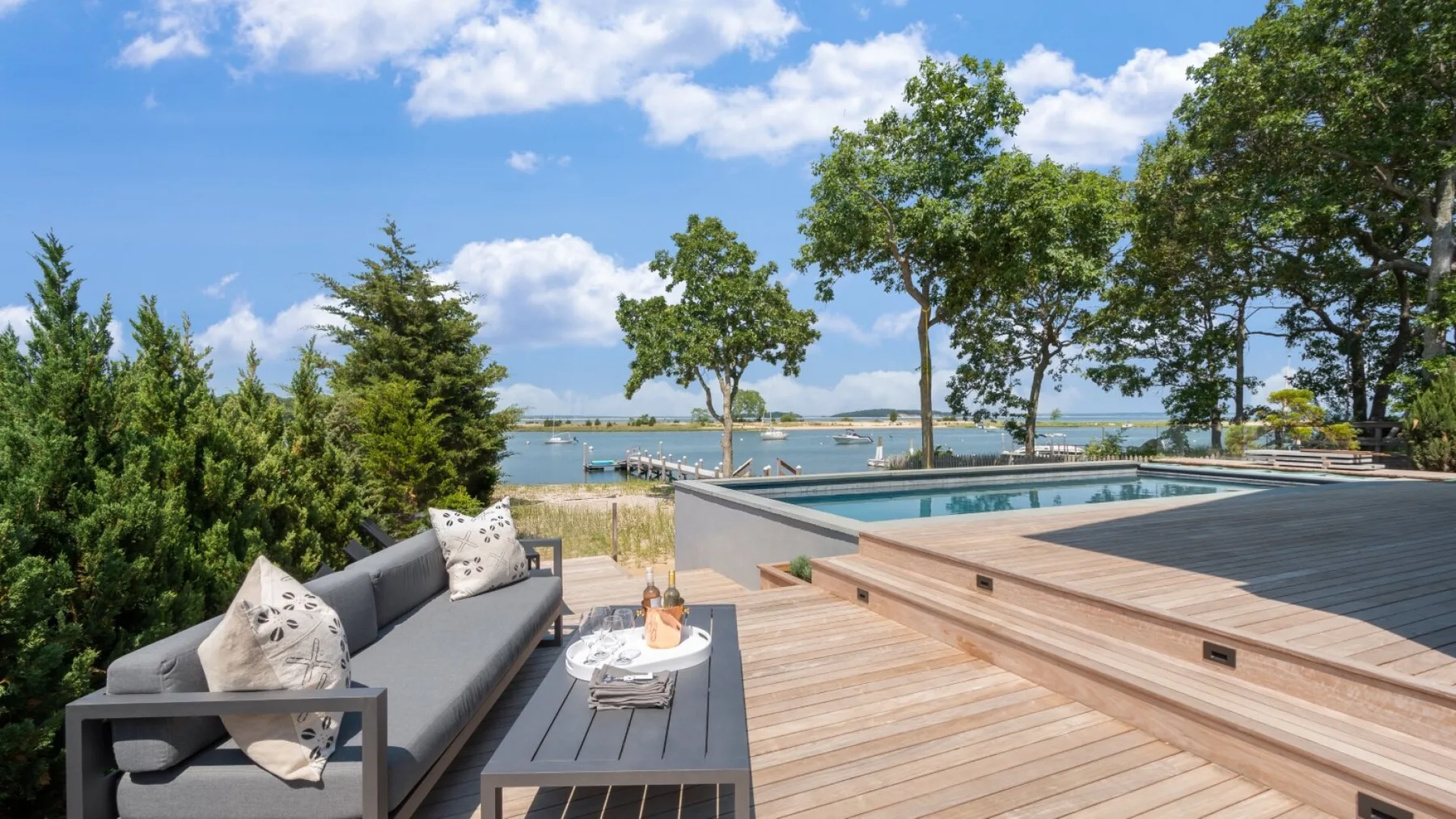 An outdoor deck with lounge seating and a pool overlooking the water.