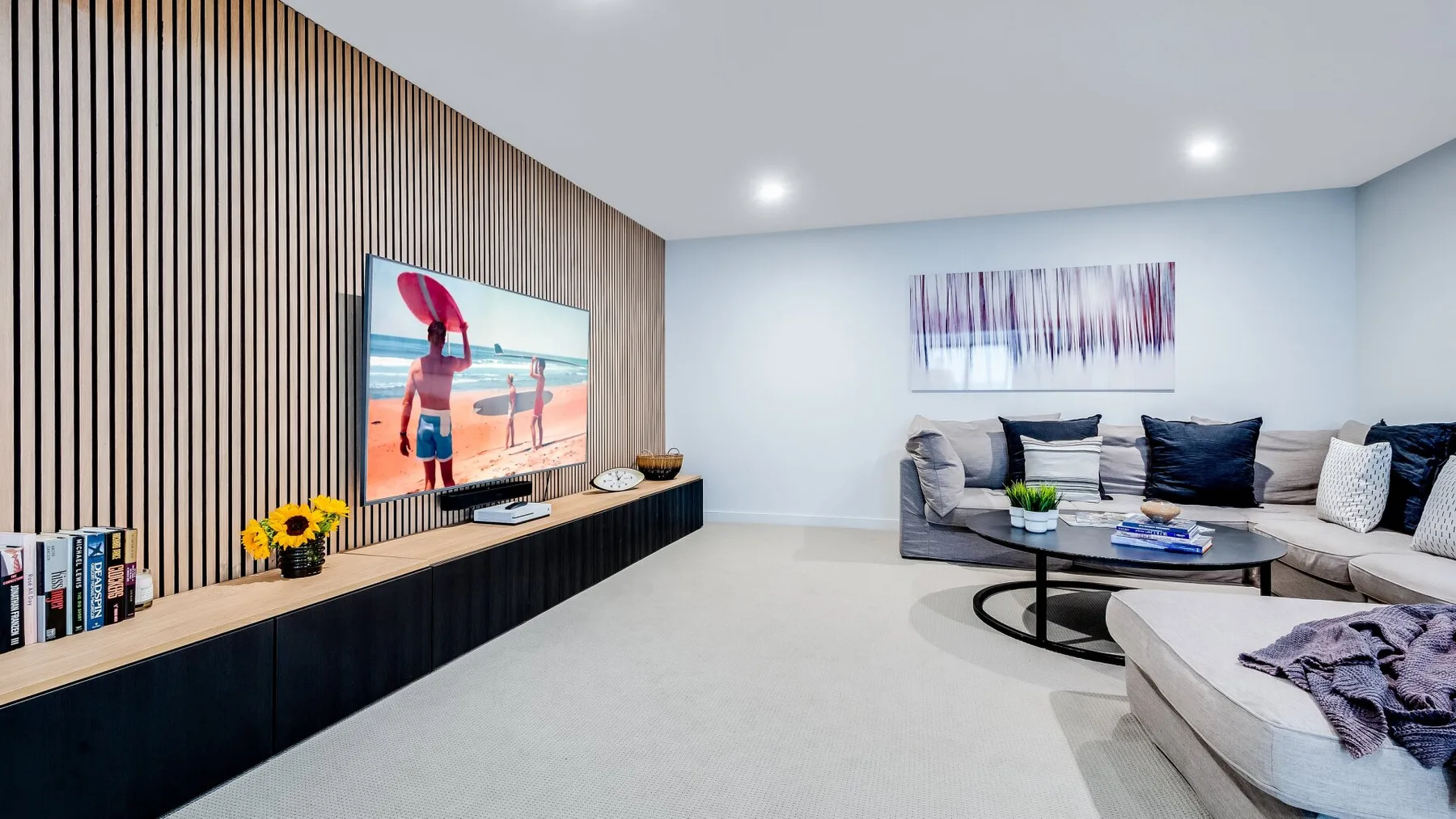 A bright living room with sectional seating, a coffee table, and a wall-mounted television.