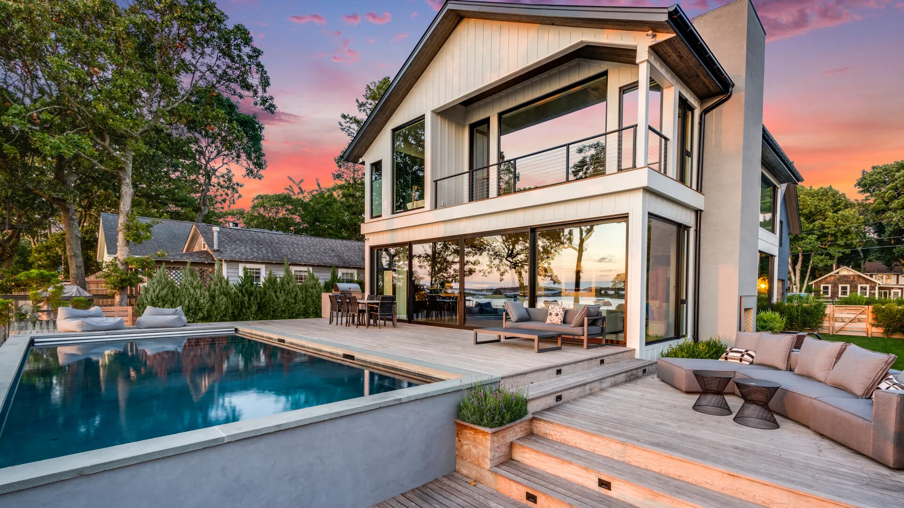 A modern house with a swimming pool and outdoor seating at sunset.