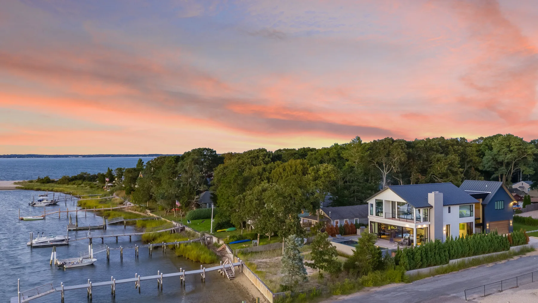 A waterfront residential scene at sunset, with homes beside a marina.