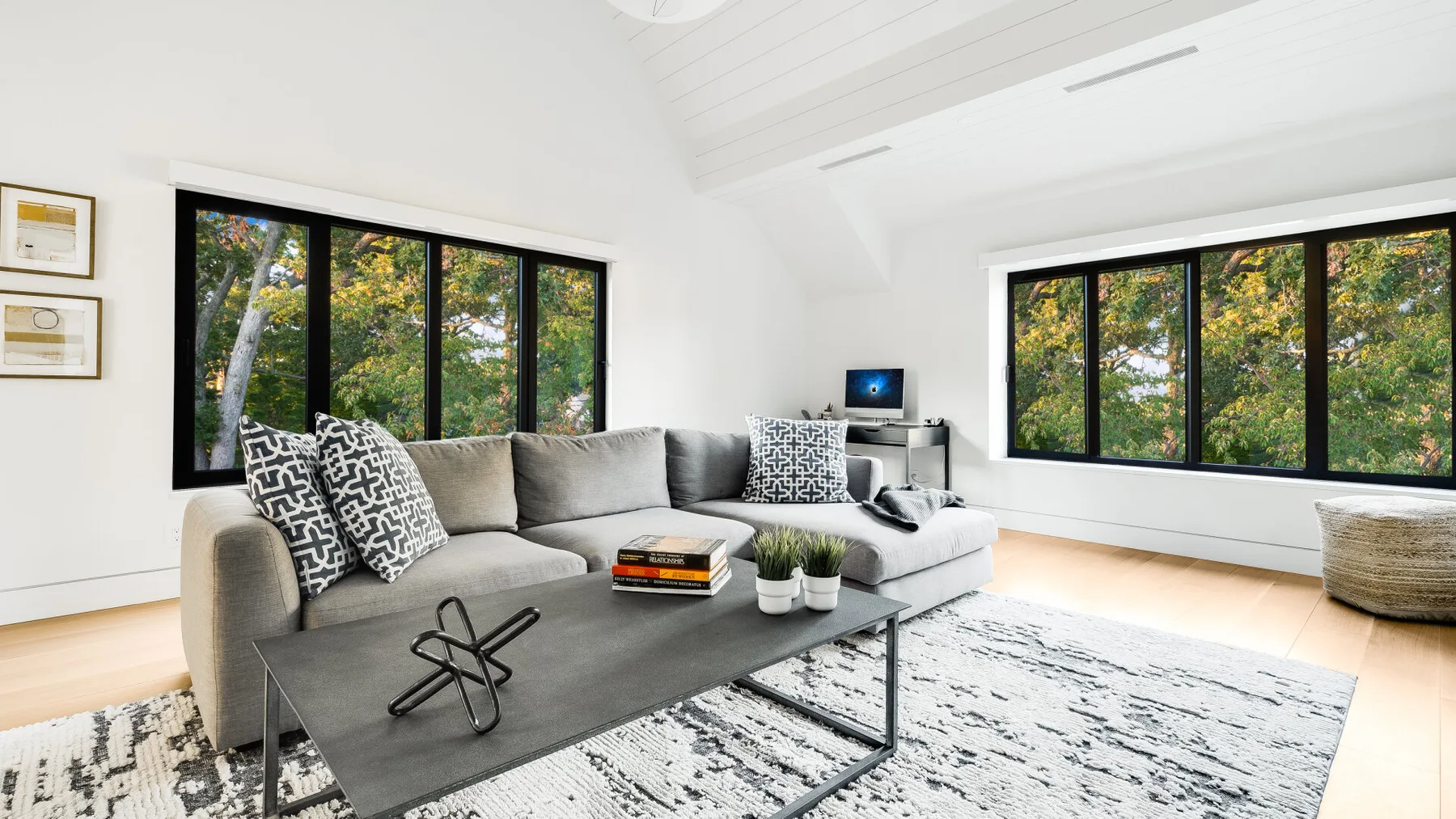 A bright living room with gray seating, a low table, and large windows.