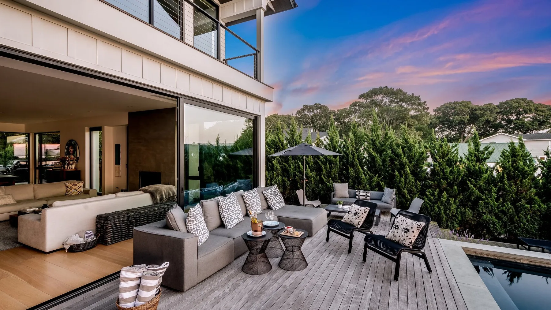 An outdoor deck with seating overlooks a pool beside a modern home.