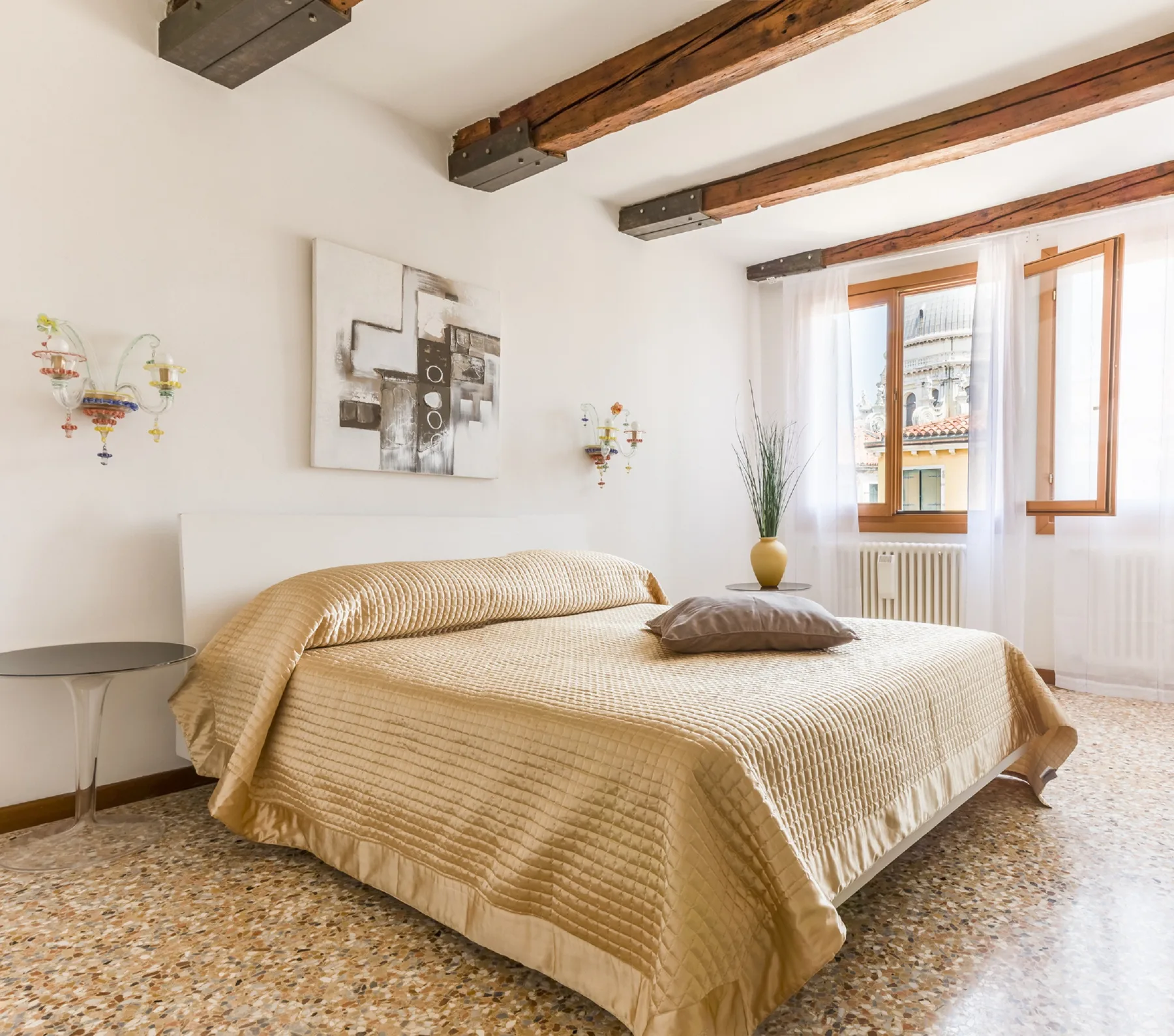 A bedroom with a large bed, wall art, and a bright window.