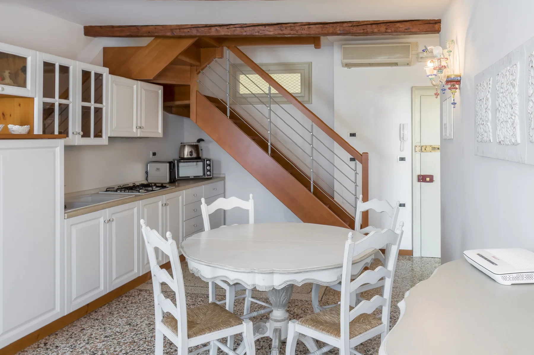 A dining area with a round table and chairs beside a staircase.
