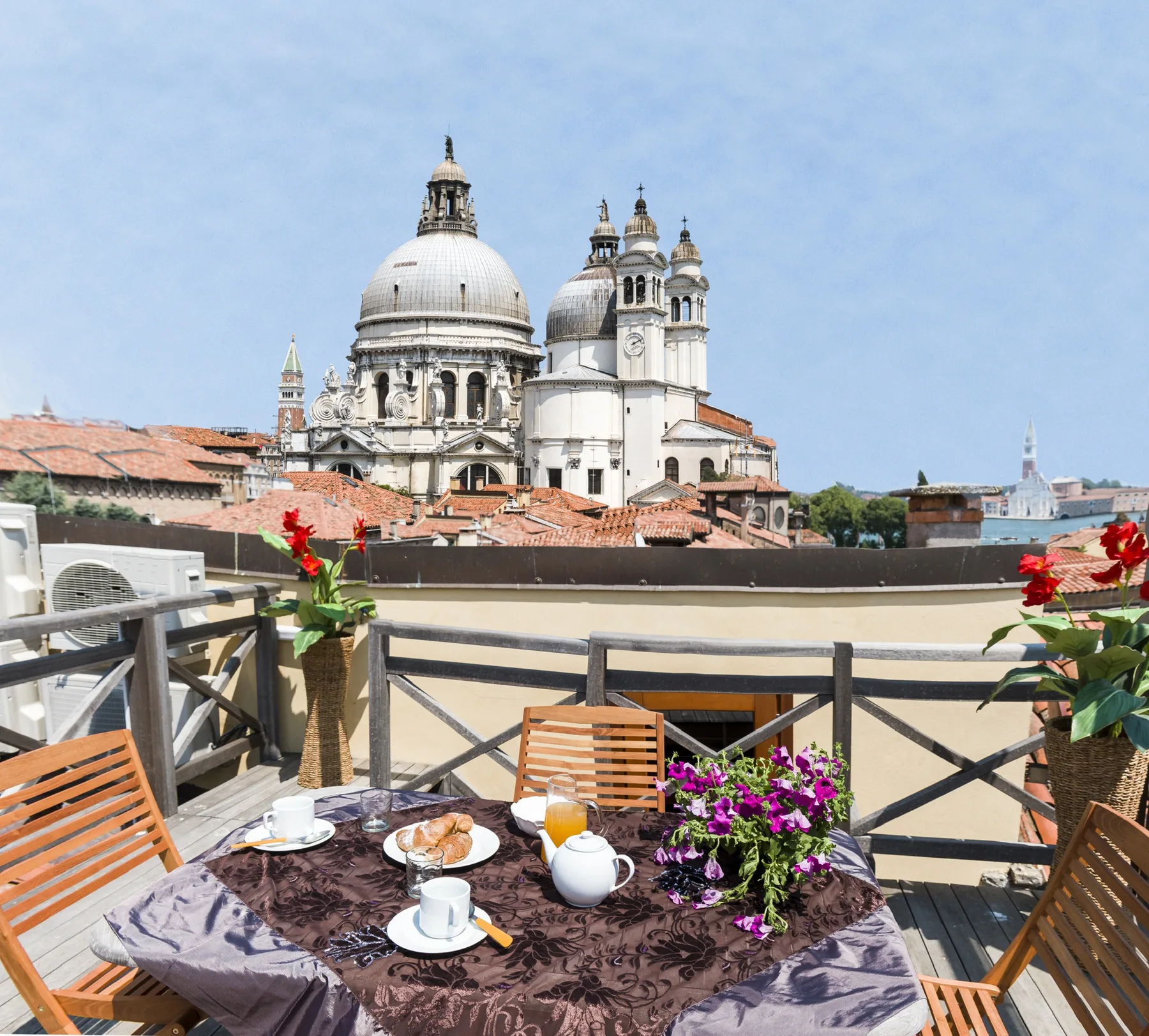A rooftop terrace has a set table and views of domed buildings.
