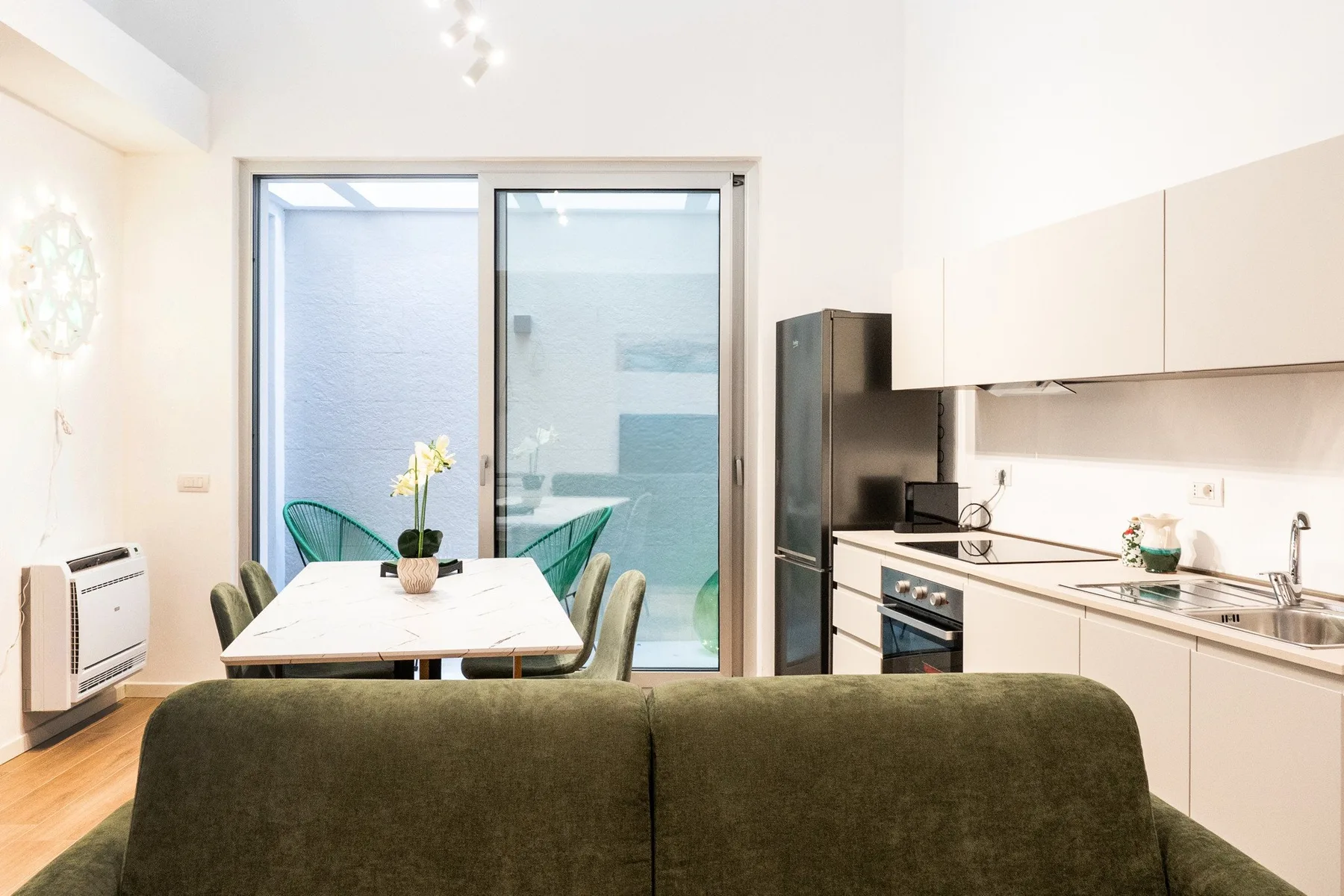 Una sala-comedor con cocina abierta y una mesa junto a grandes ventanales.