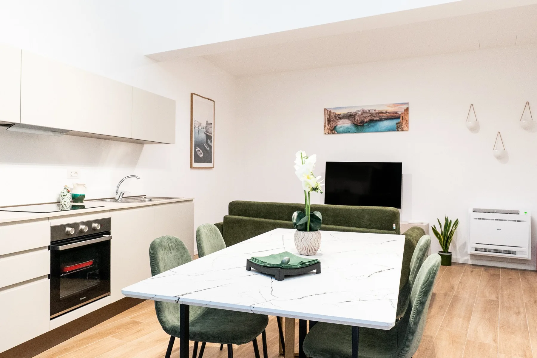 Una luminosa cocina-comedor diáfana con una mesa y un televisor.