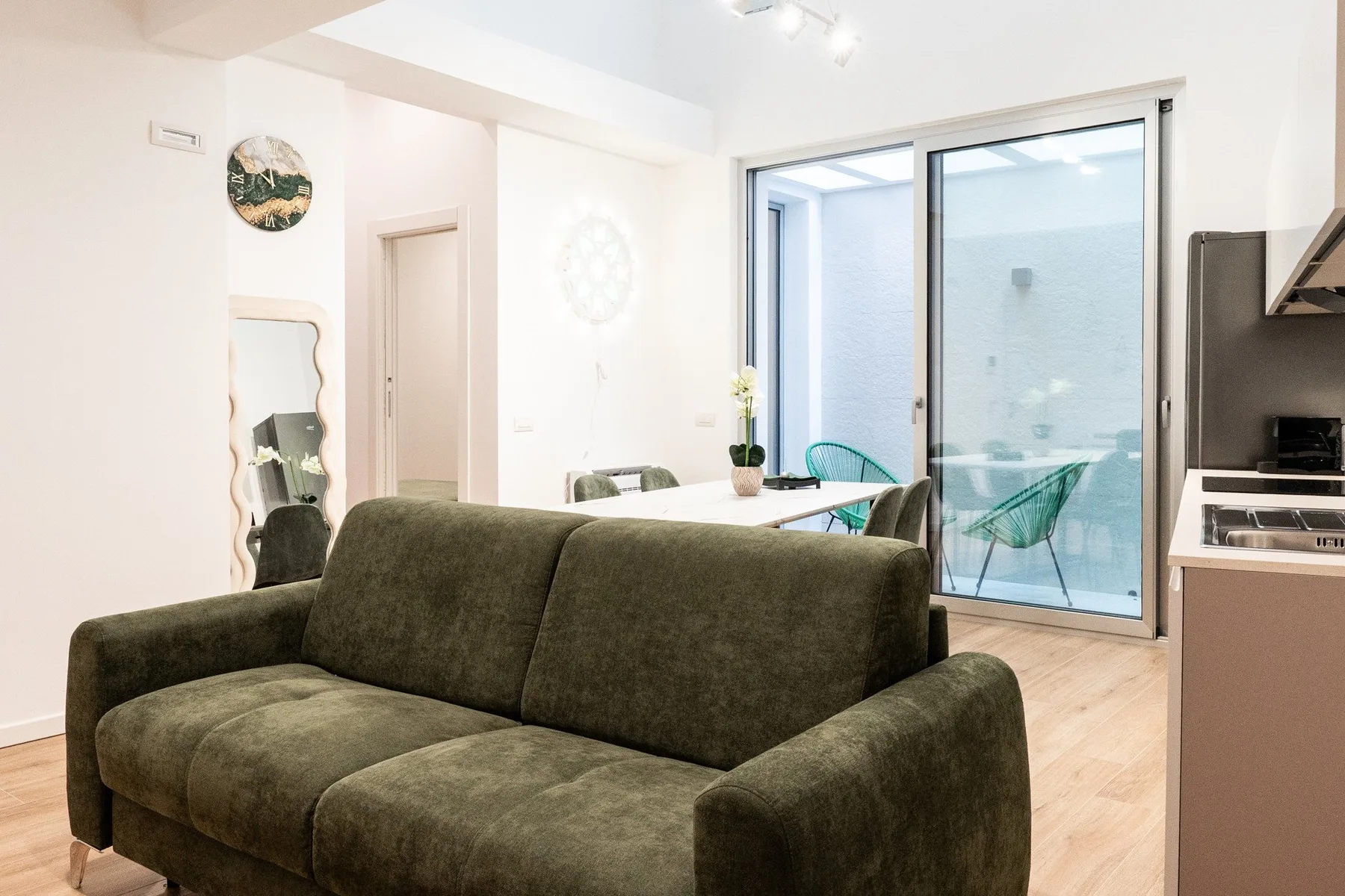 Una sala luminosa con un sofá oscuro junto a grandes puertas corredizas de vidrio.