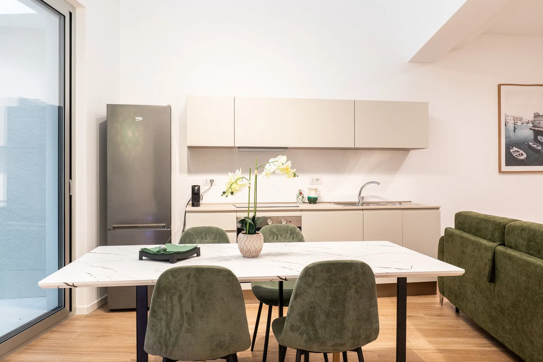 Comedor con una mesa y asientos verdes junto a una cocina compacta.