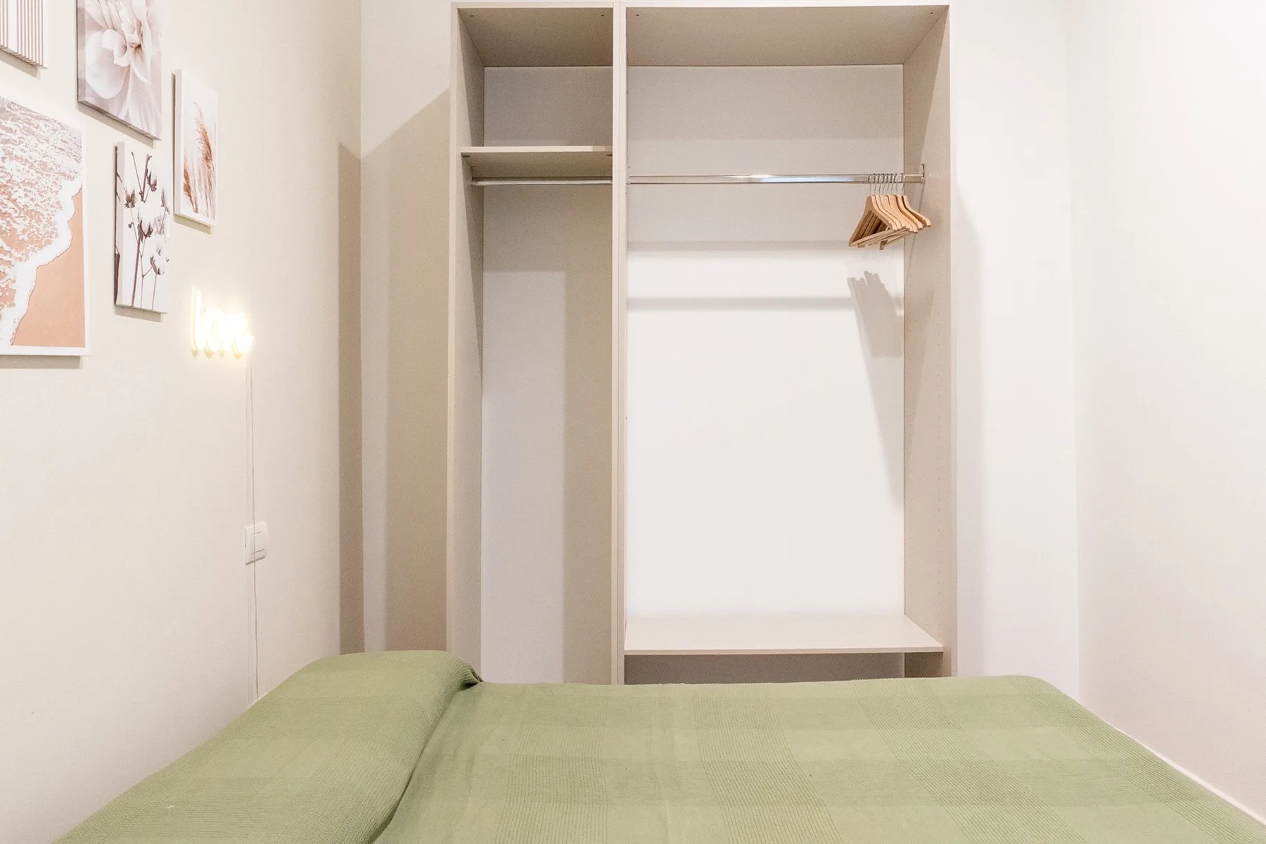 Un dormitorio con ropa de cama verde y un armario abierto.