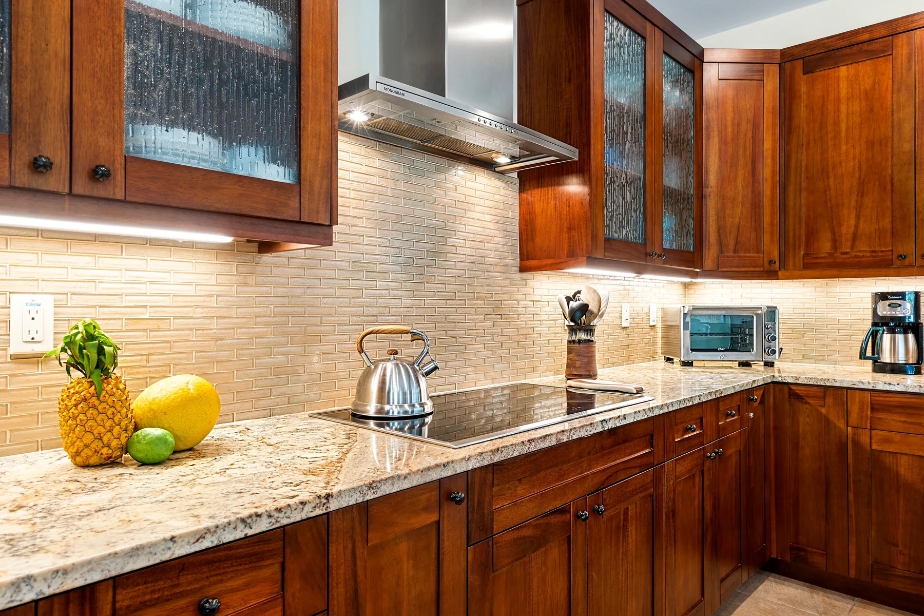 Una cocina con armarios de madera, una encimera y una placa de cocina.