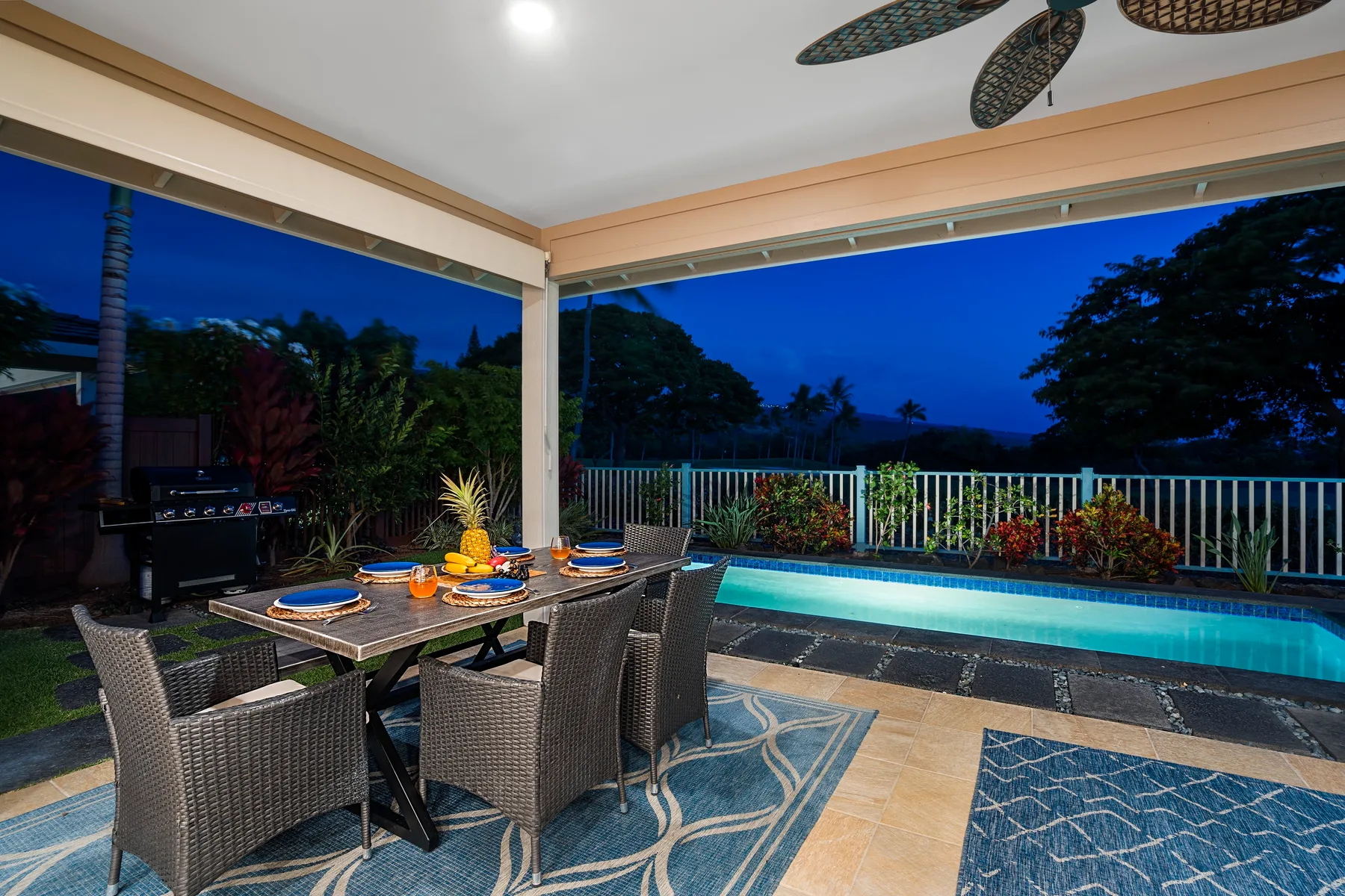 Comedor exterior cubierto junto a una piscina, con una mesa y asientos.