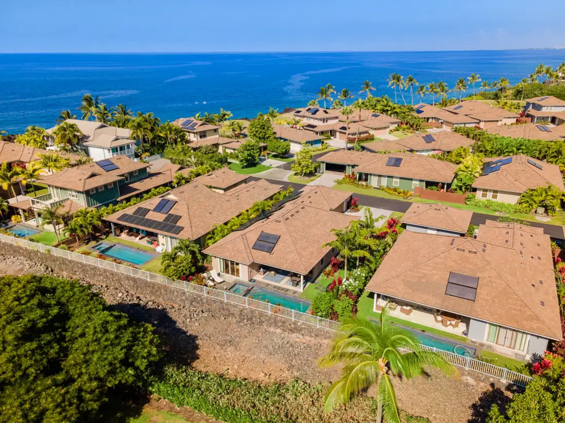 Vista aérea de casas costeras con palmeras junto al océano.